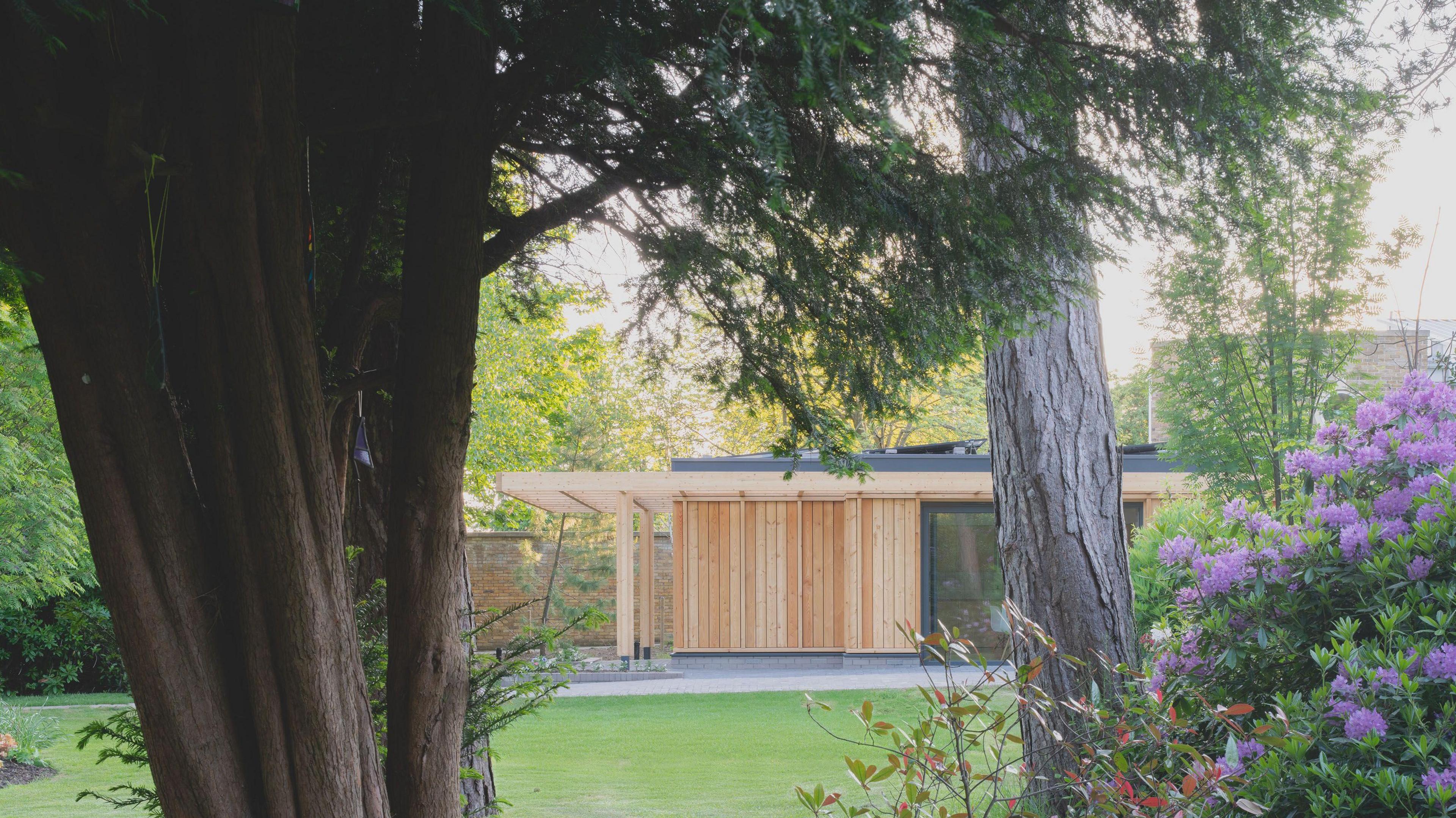 A timber building in the background, with trees and a lawn in the foreground