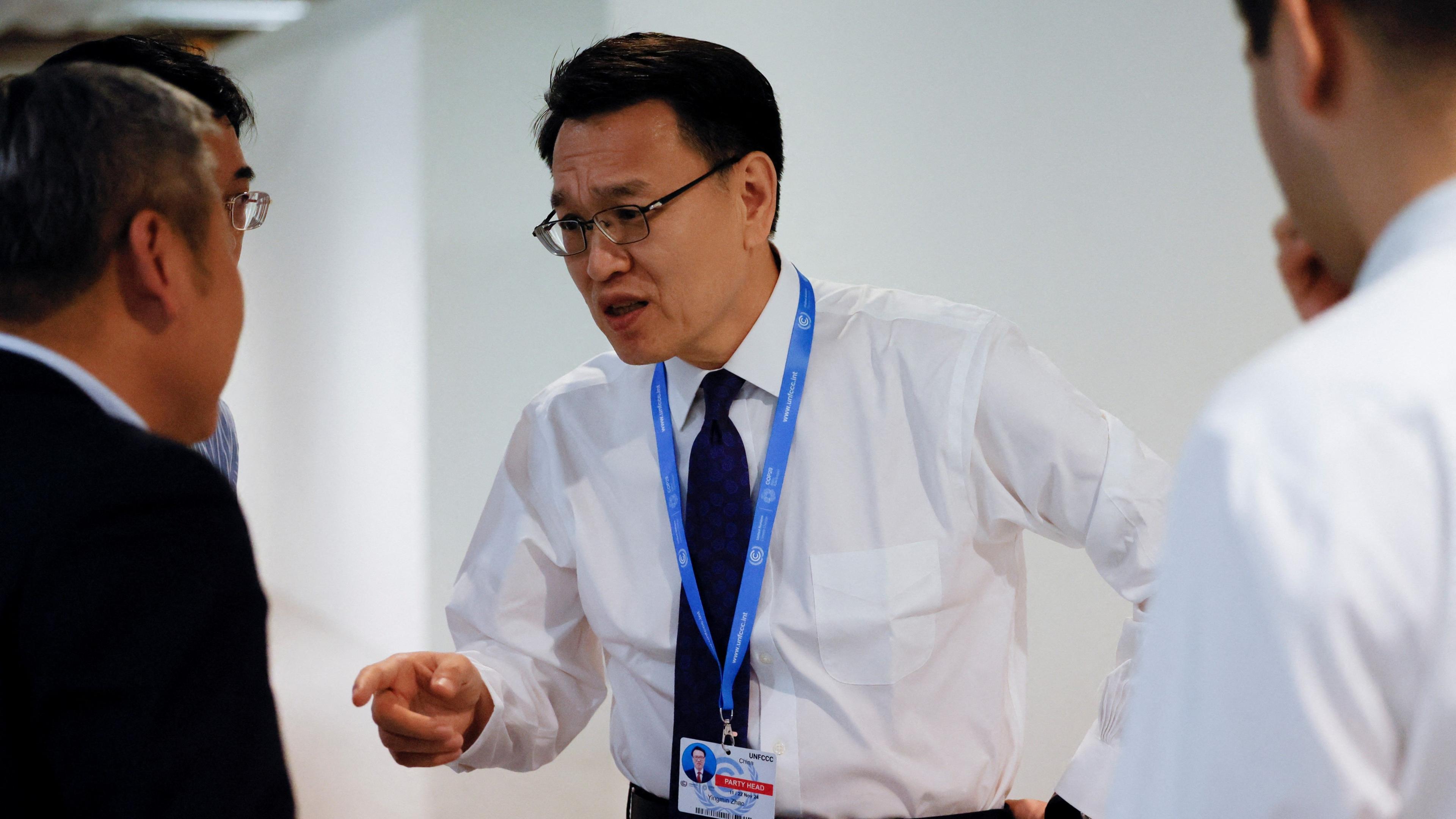 China's Vice Minister of Ecology and Environment Zhao Yingmin, in a white shirt, black tie and conference lanyard, points as he speaks with others at the COP29 United Nations Climate Change Conference, in Baku, Azerbaijan on 23 November