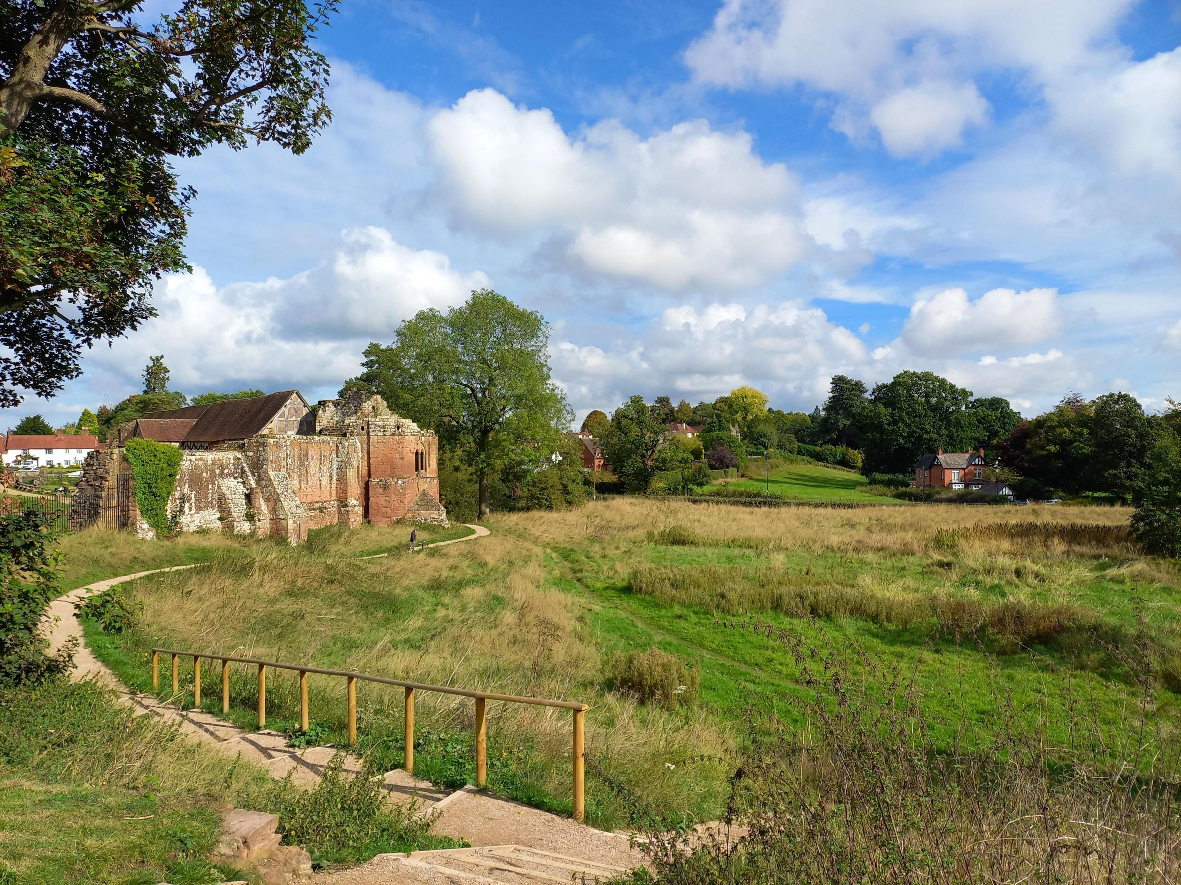 A field with a path, ruins of a old house and blue skies with some clouds 