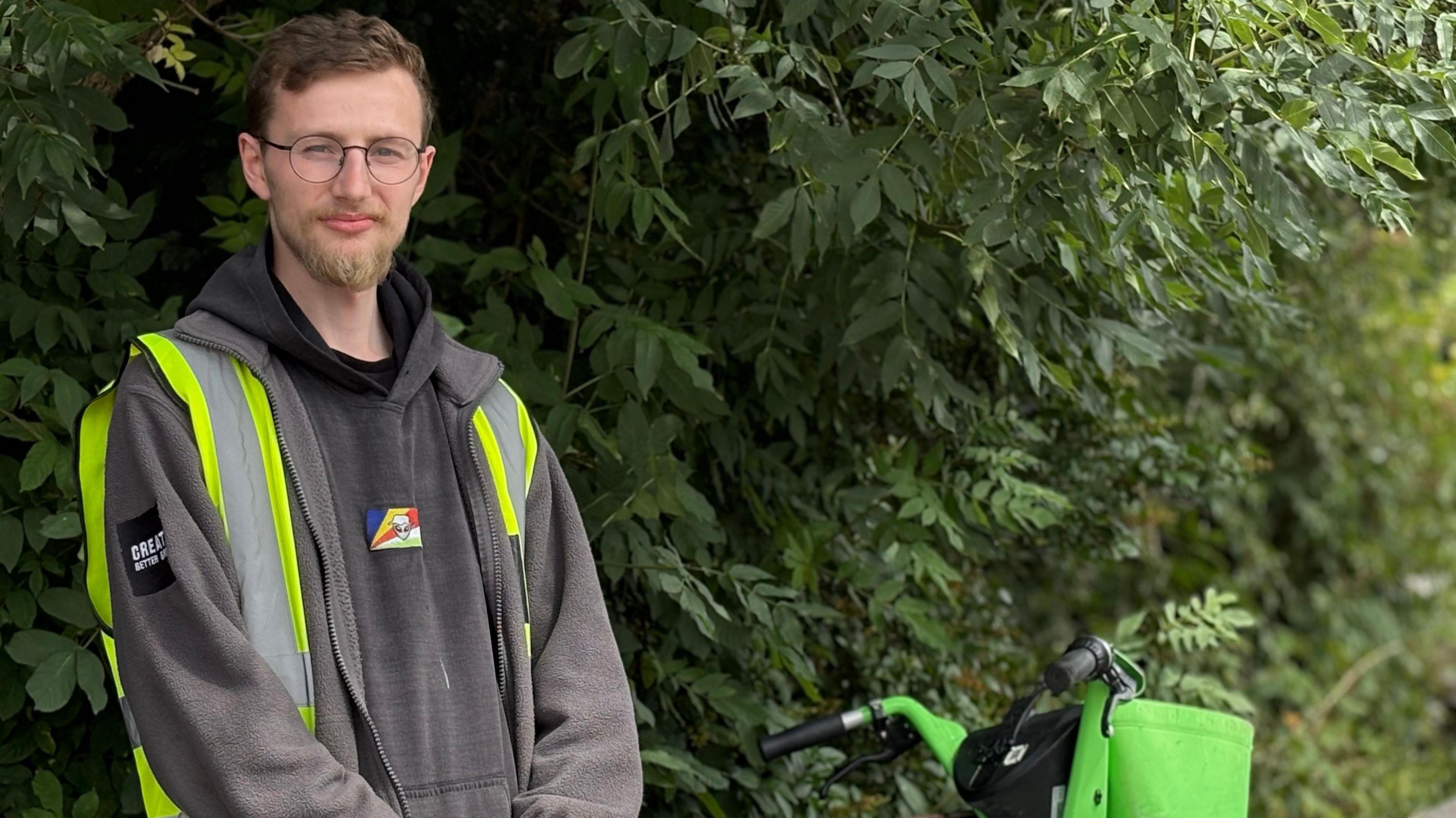 Declan Anthony stood by a ebike in front of some trees