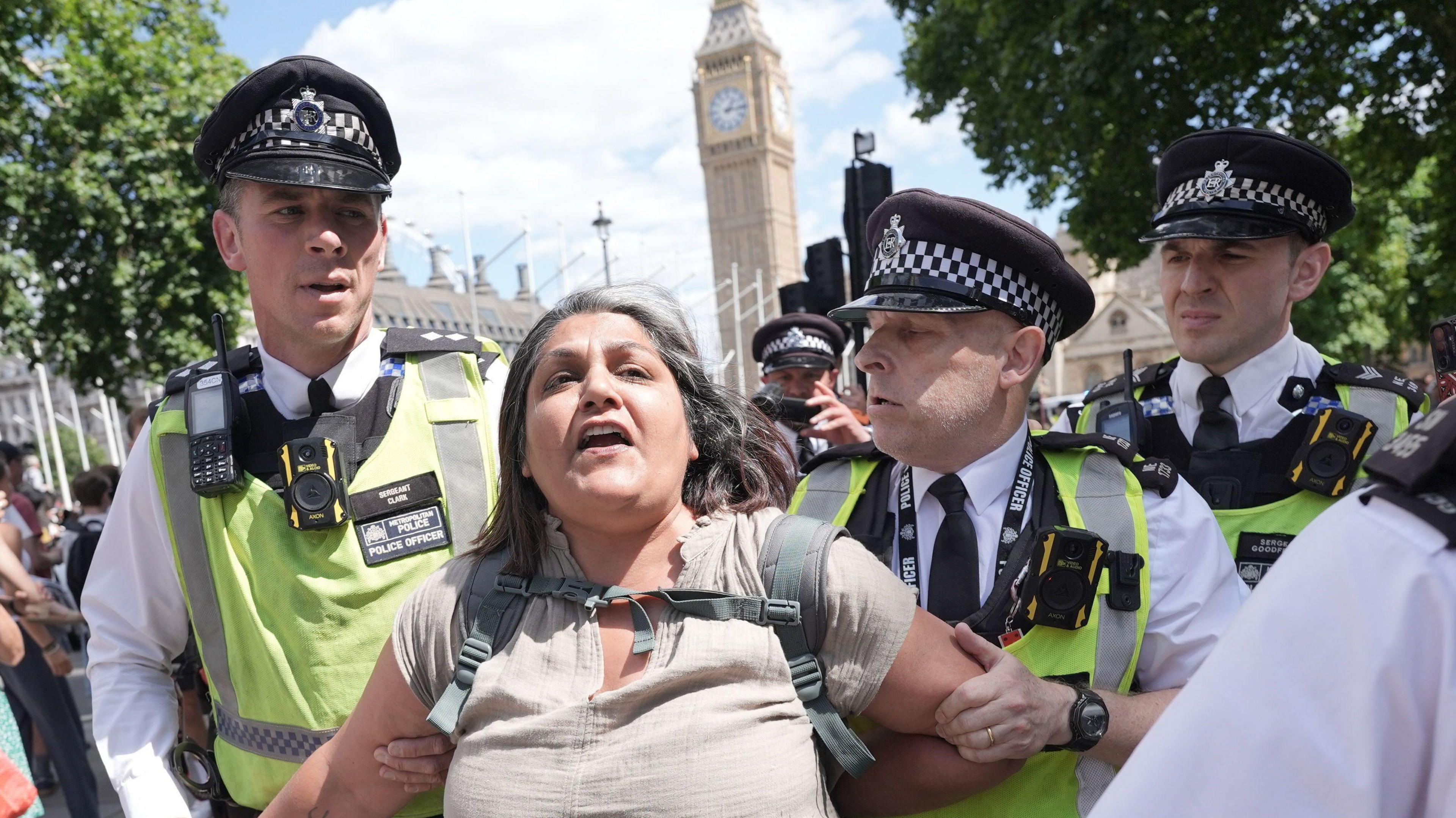 A woman is led away by police officers as supporters of Palestine Action take part in a protest in Parliament Square, Westminster