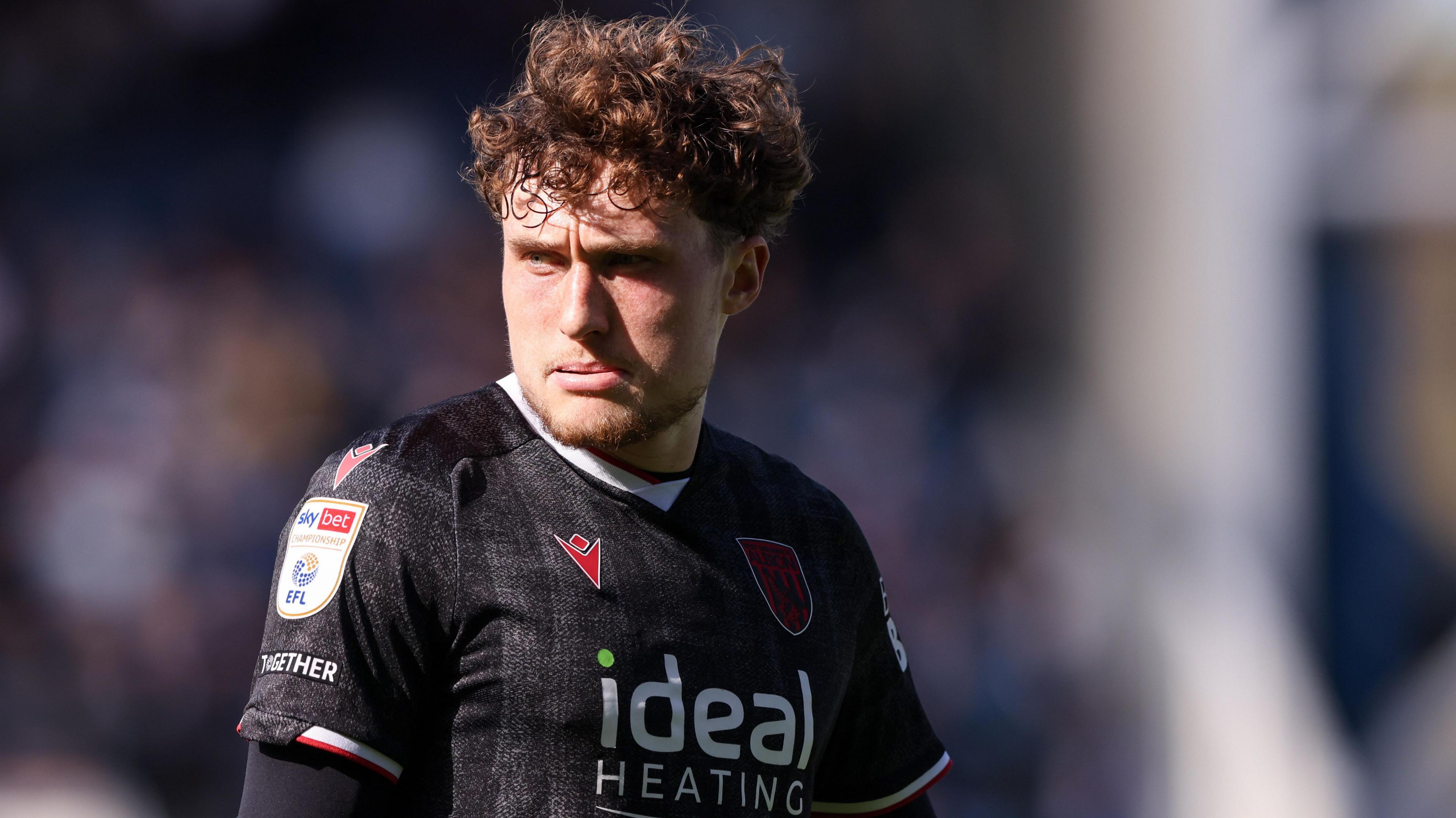 West Bromwich Albion defender Callum Styles looks to his right during a game. He is wearing a black club away shirt.