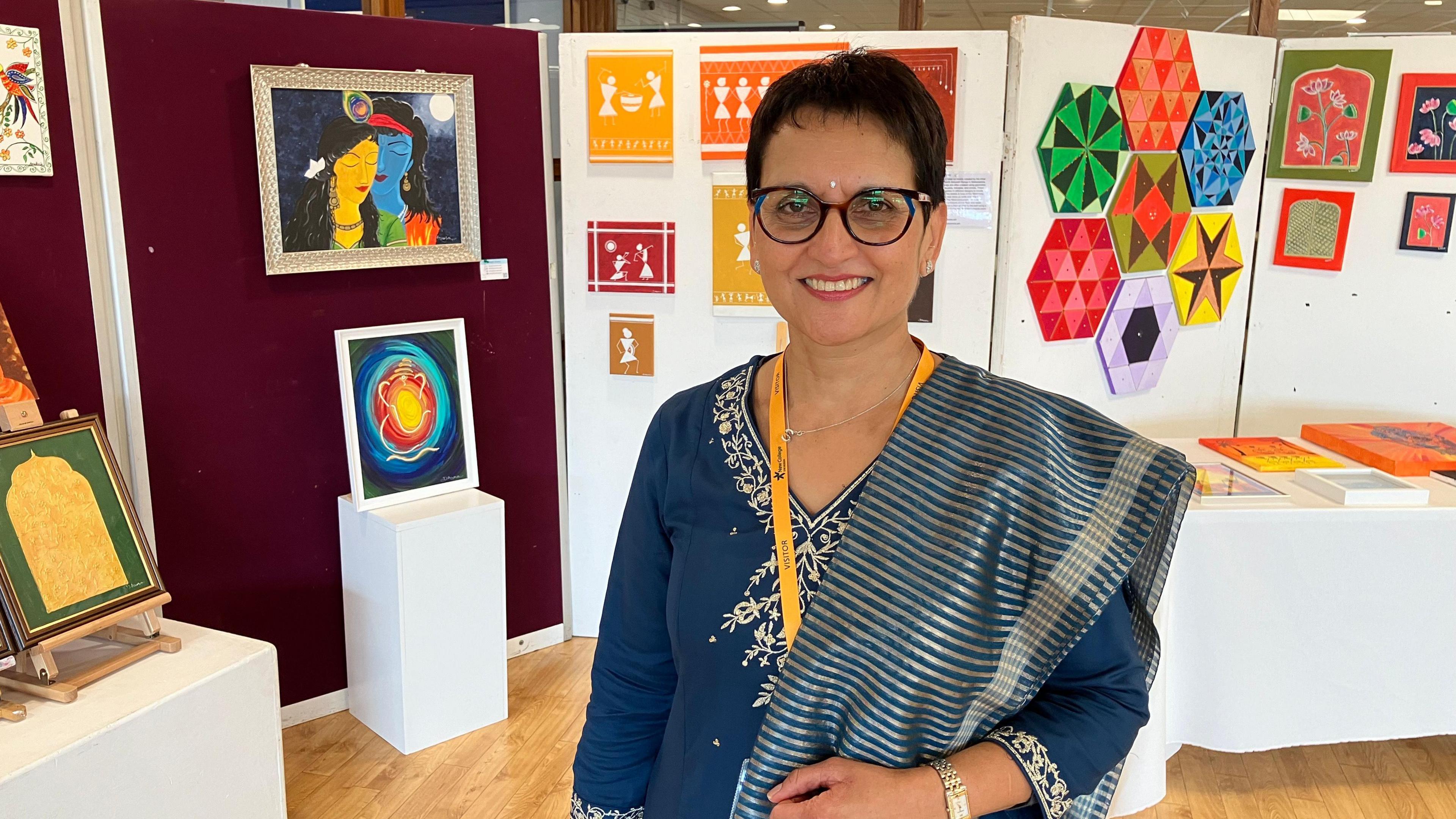 Sushma Patel wearing traditional Indian clothing and standing in front of a cultural display