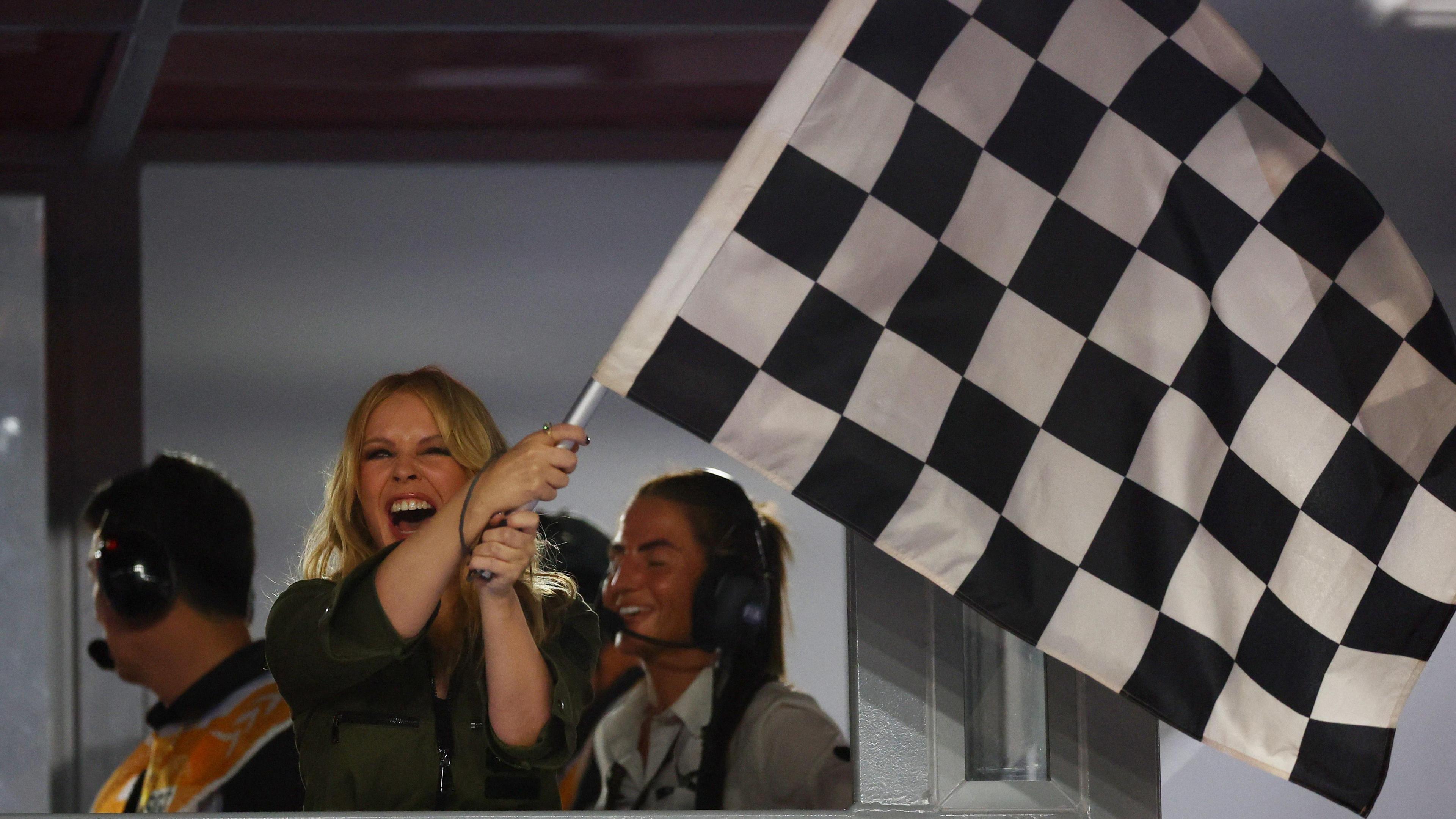 Kylie Minogue waves the chequered flag at the end of the Singapore Grand Prix