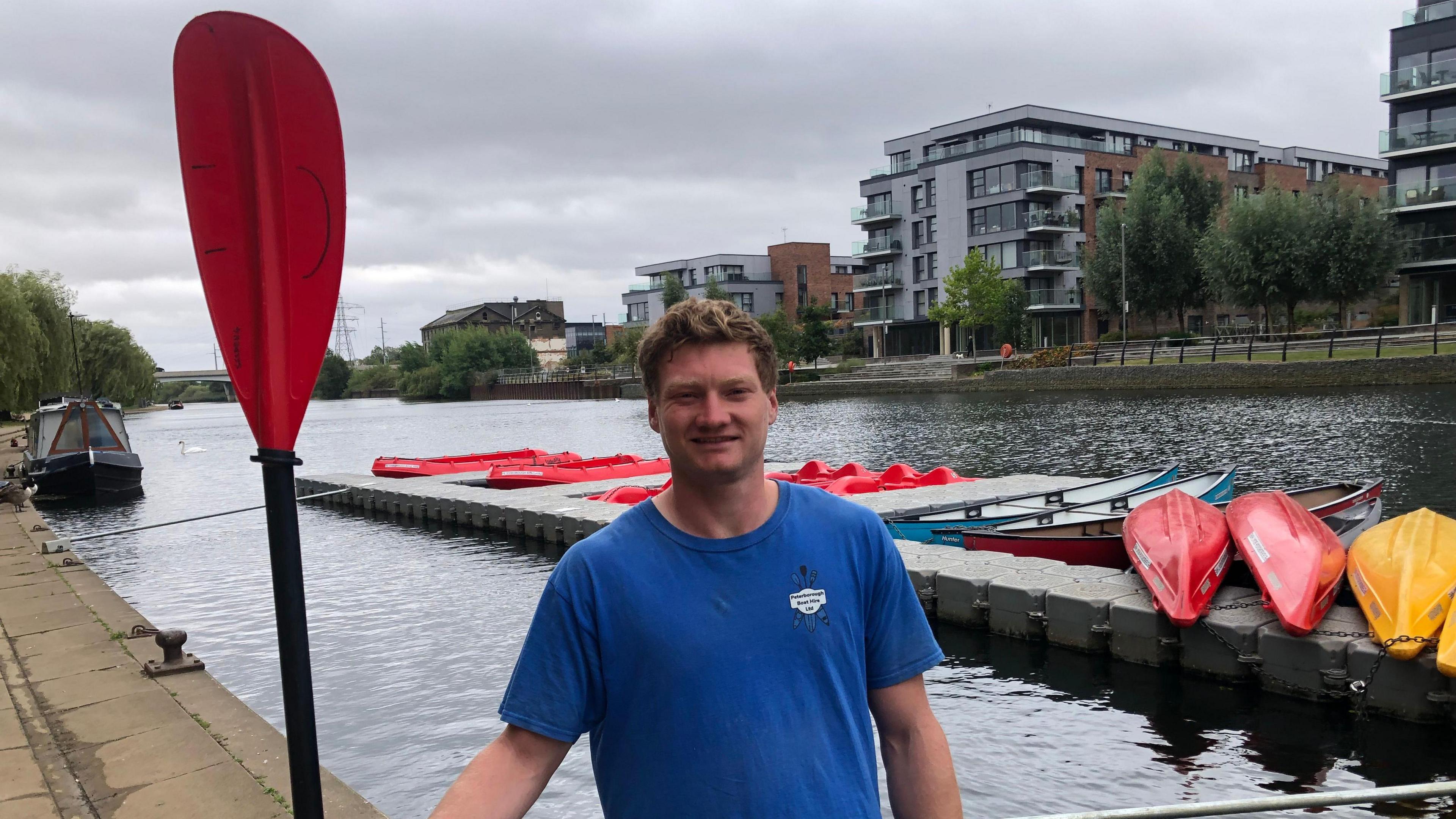 Byron Cripps standing with an oar near some boats