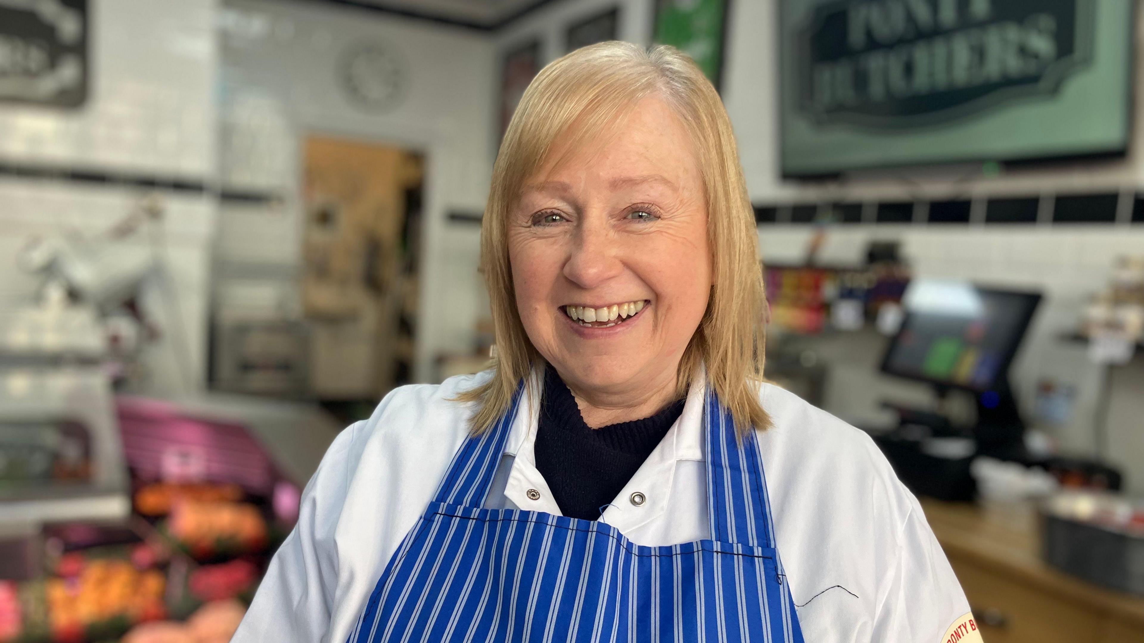 Cigydd Julie Jones mewn ffedog streipiog las