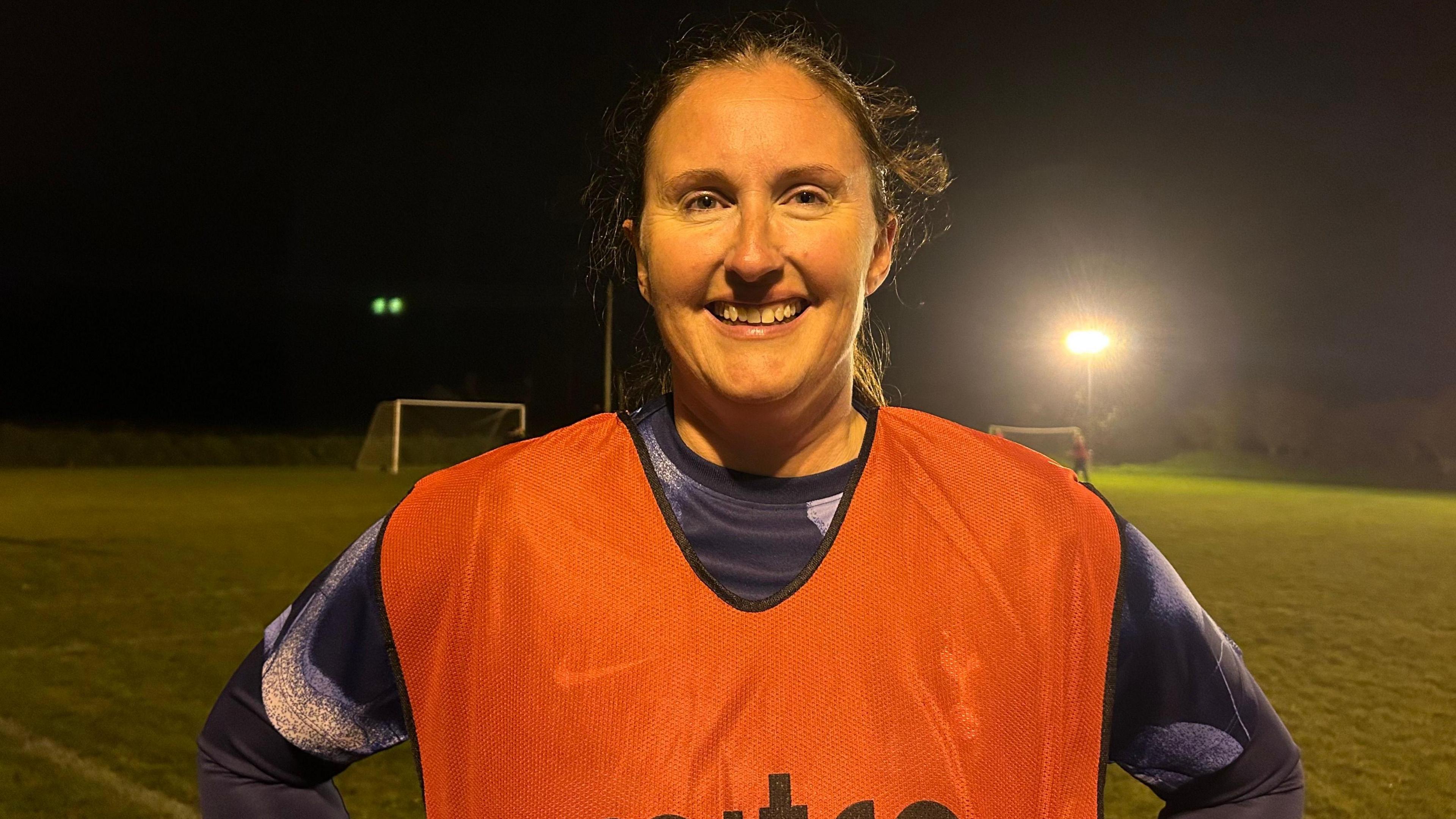 Julie Simon on a football pitch smiling for the camera