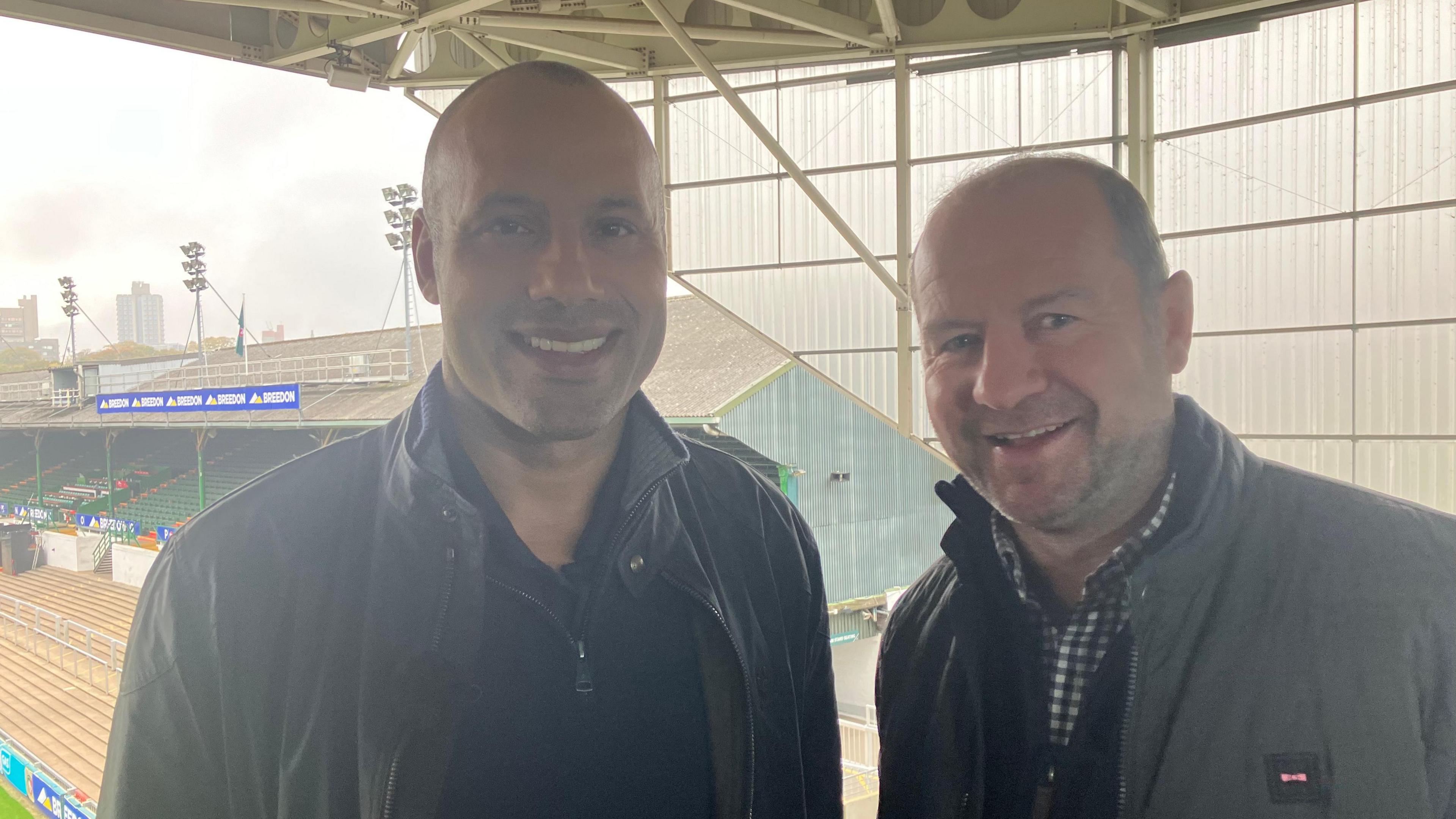 Leon and Geordan smiling for the camera with Welford Road Stadium in the background. 