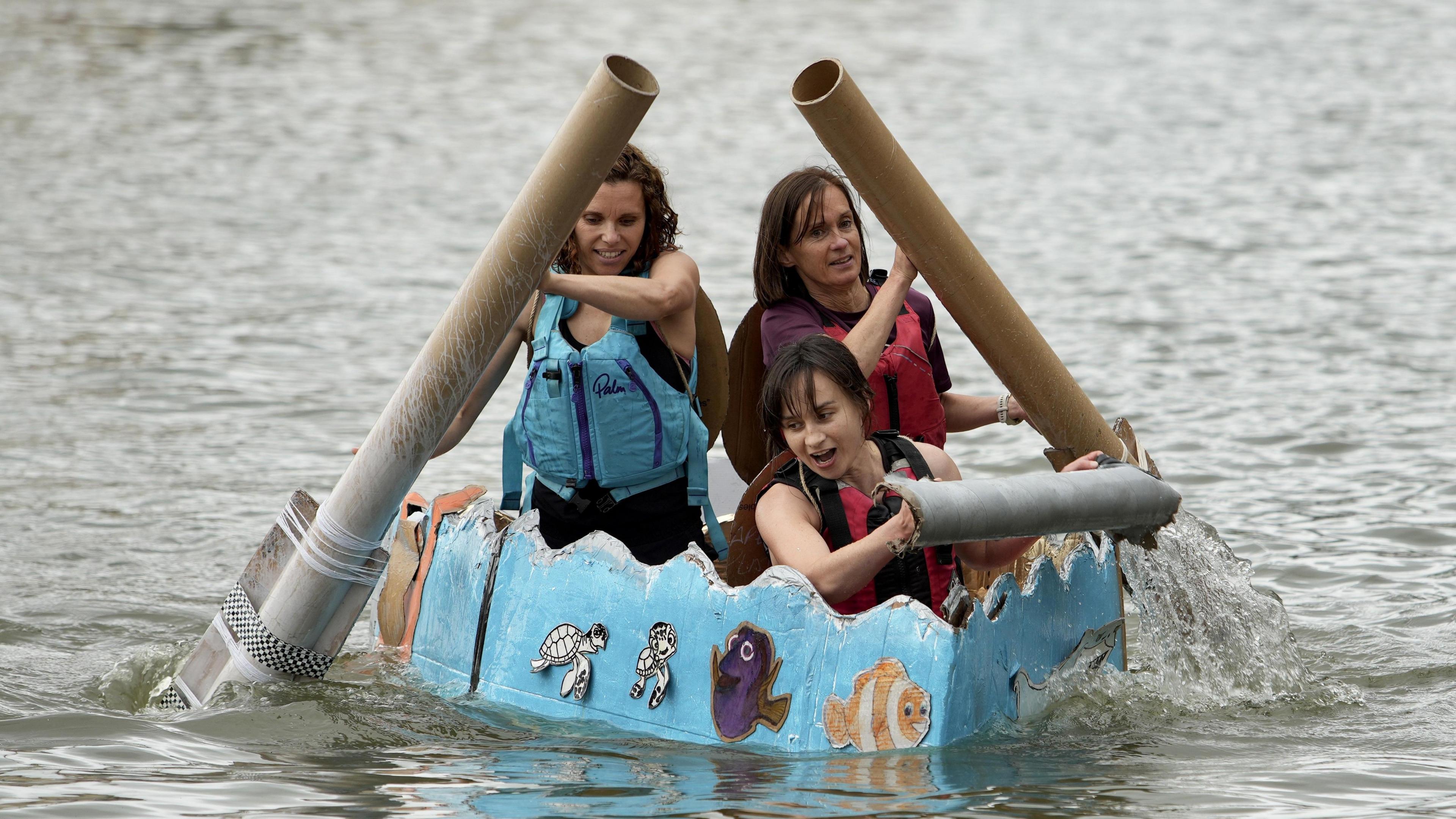 A group of three women take part in the cardboard boat race at the Bristol Harbour Festival