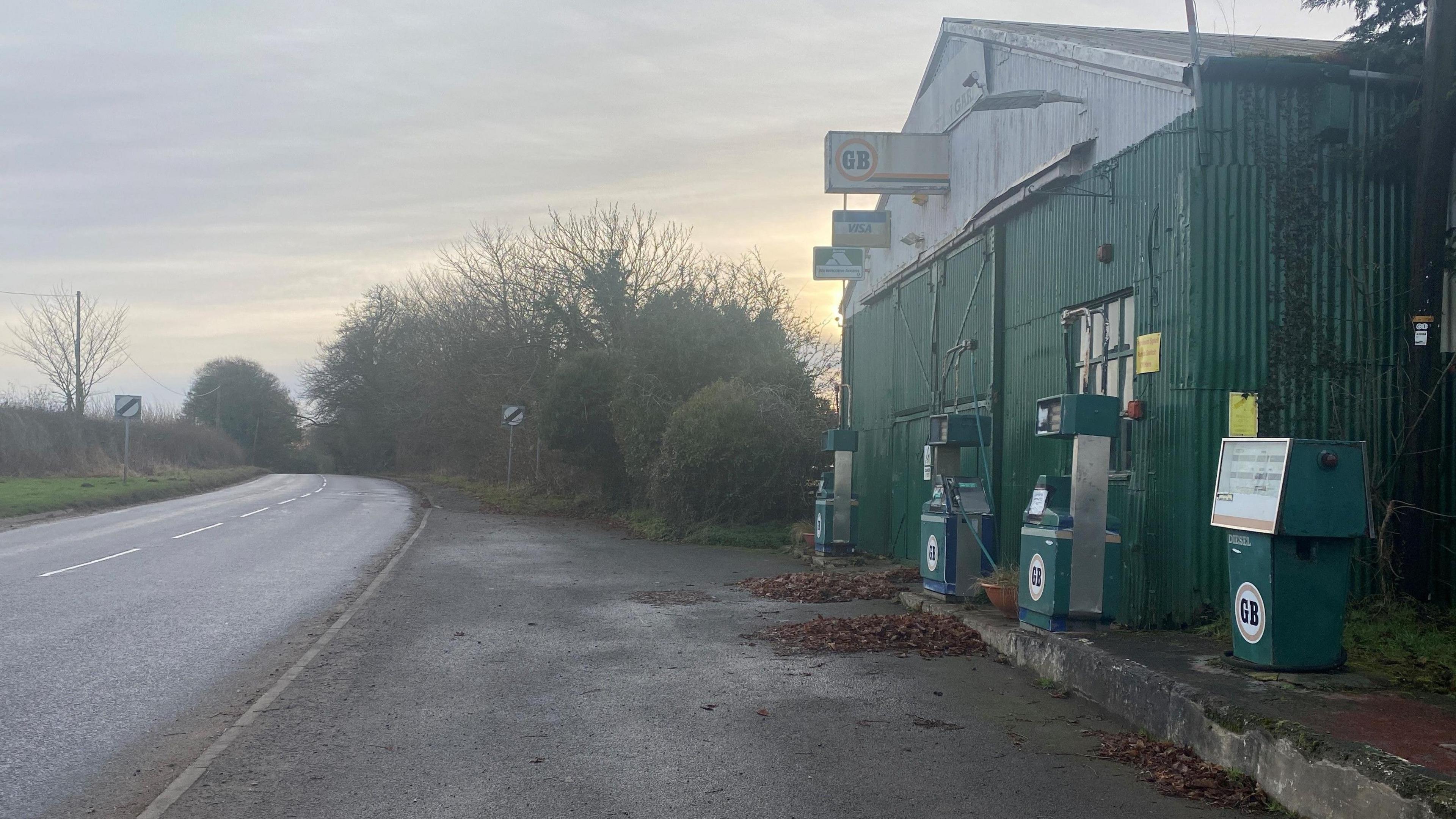 A road outside the village of Felton with some old petrol pumps in front of now closed garage.