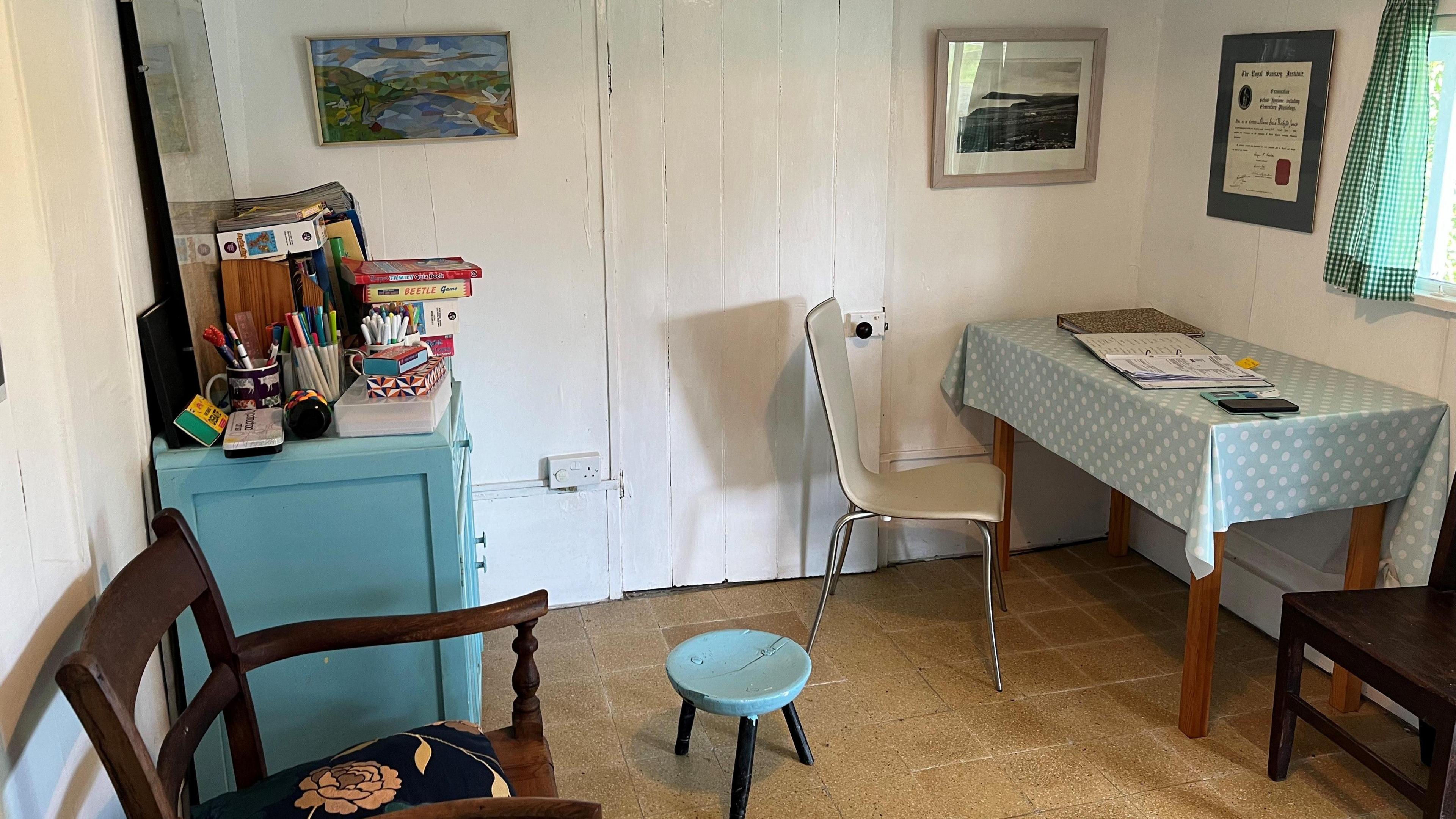 An interior view of the bungalow, showing a table and chair as well as a blue chest of drawers