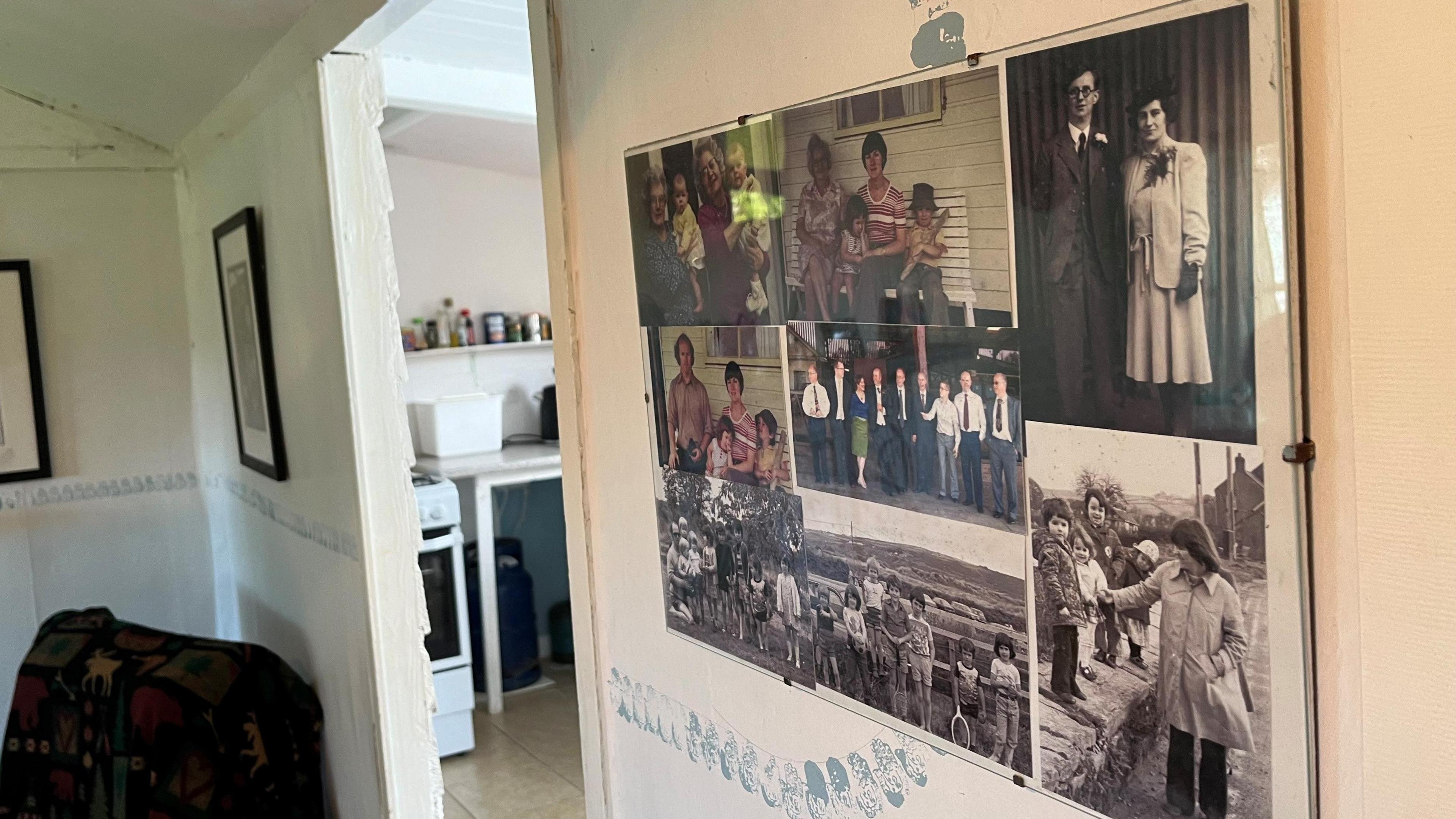 Family photos on the wall of the interior of the bungalow, an over can be seen in the doorway behind