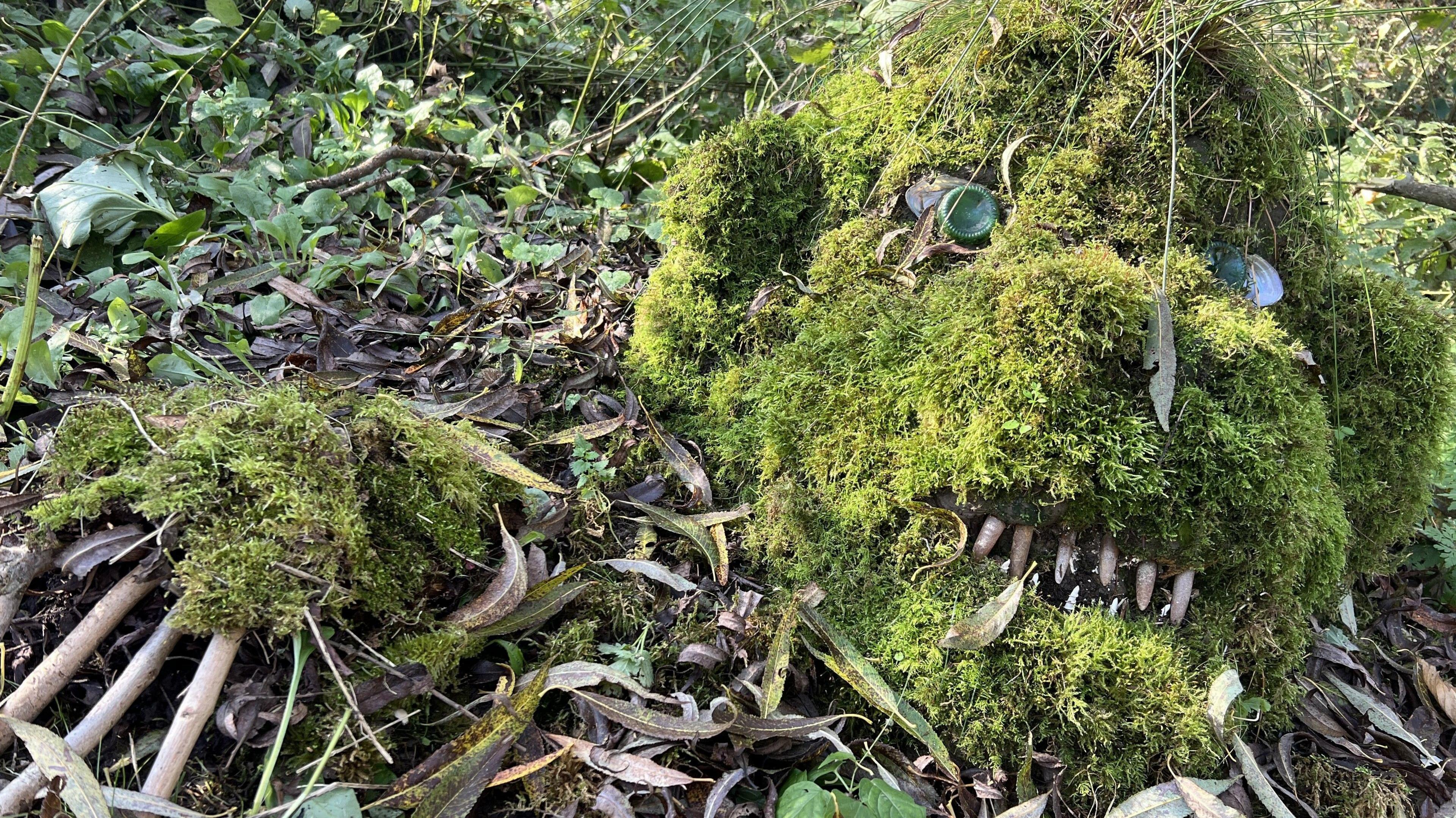 A sculpture of a mythical creature made from of moss, stone, leaves and earth