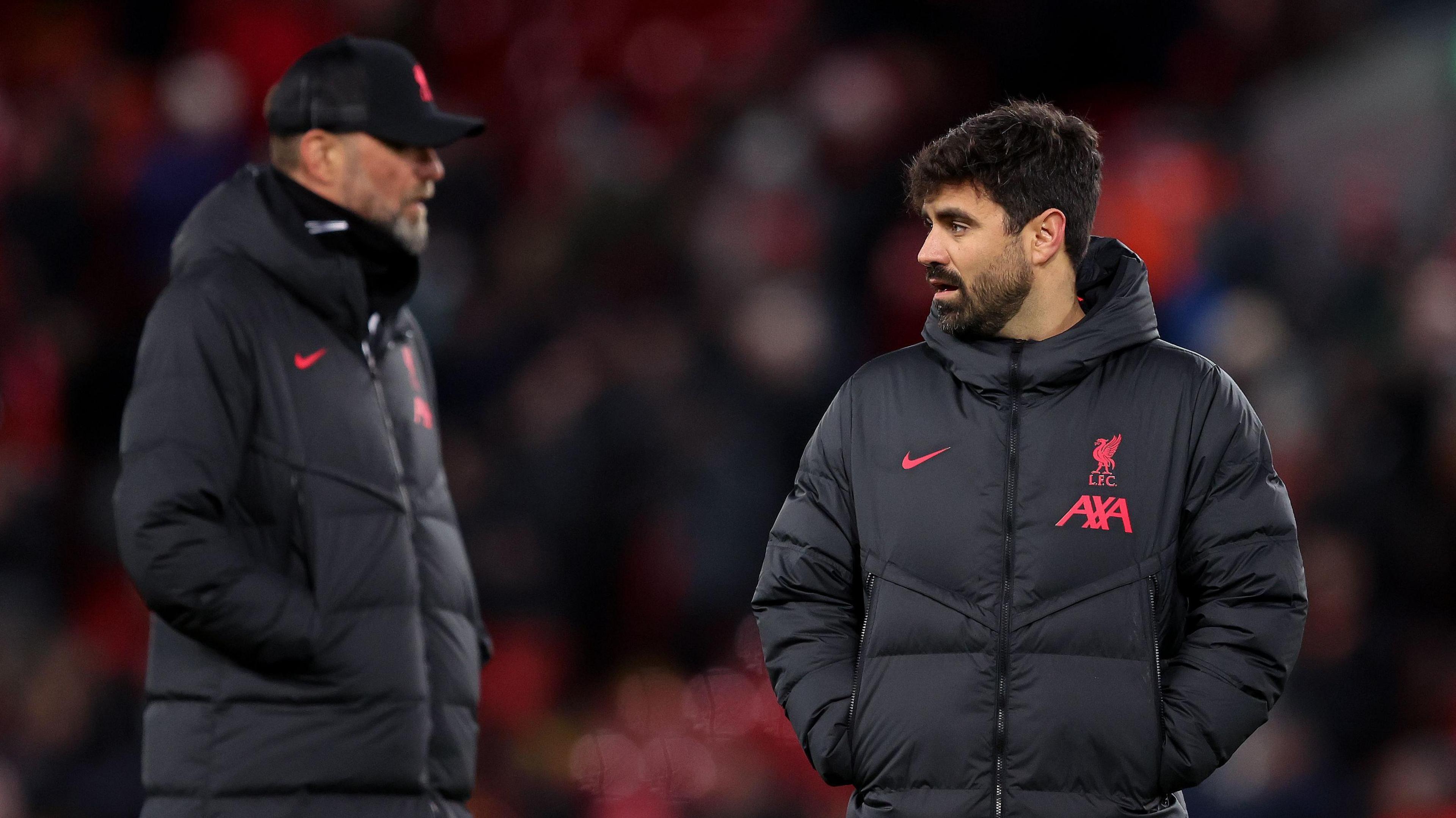 Jurgen Klopp on the left and Vitor Matos on the right look at each other wearing dark coats