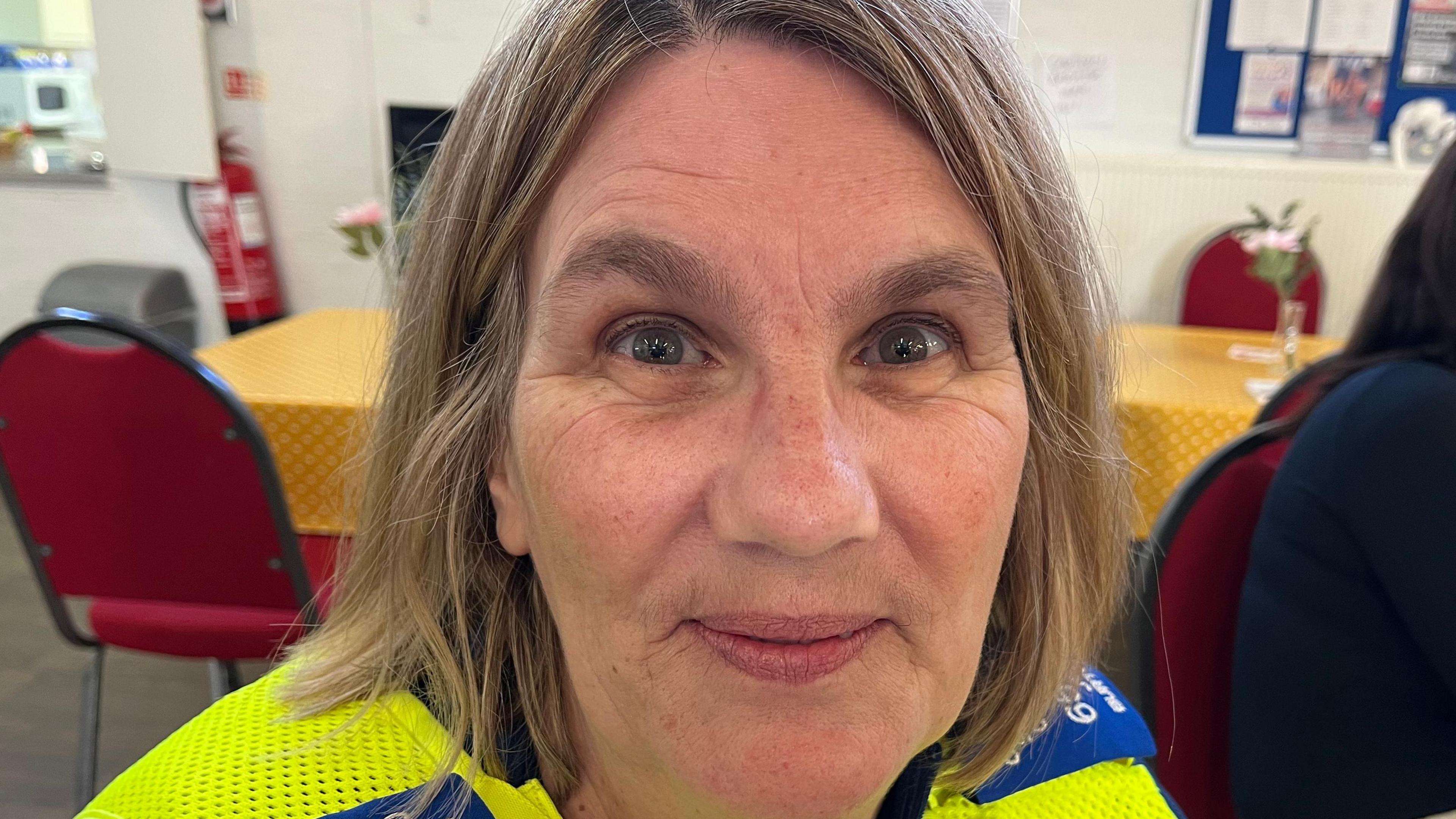 Jo Burton smiles at the camera wearing uniform with a community centre in the background. 