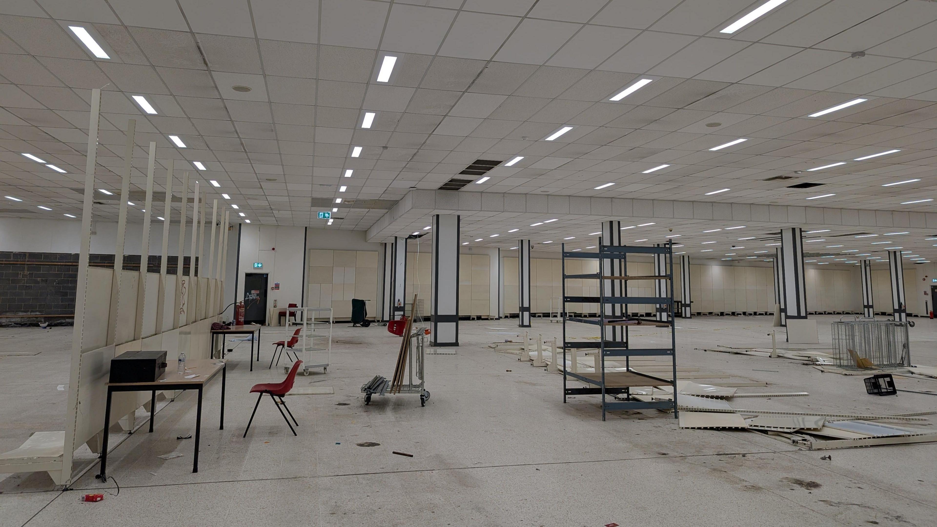 The inside of the former Wilko store. Wall partitions have been knocked over and torn apart. Broken walls and trolleys litter the large white room.