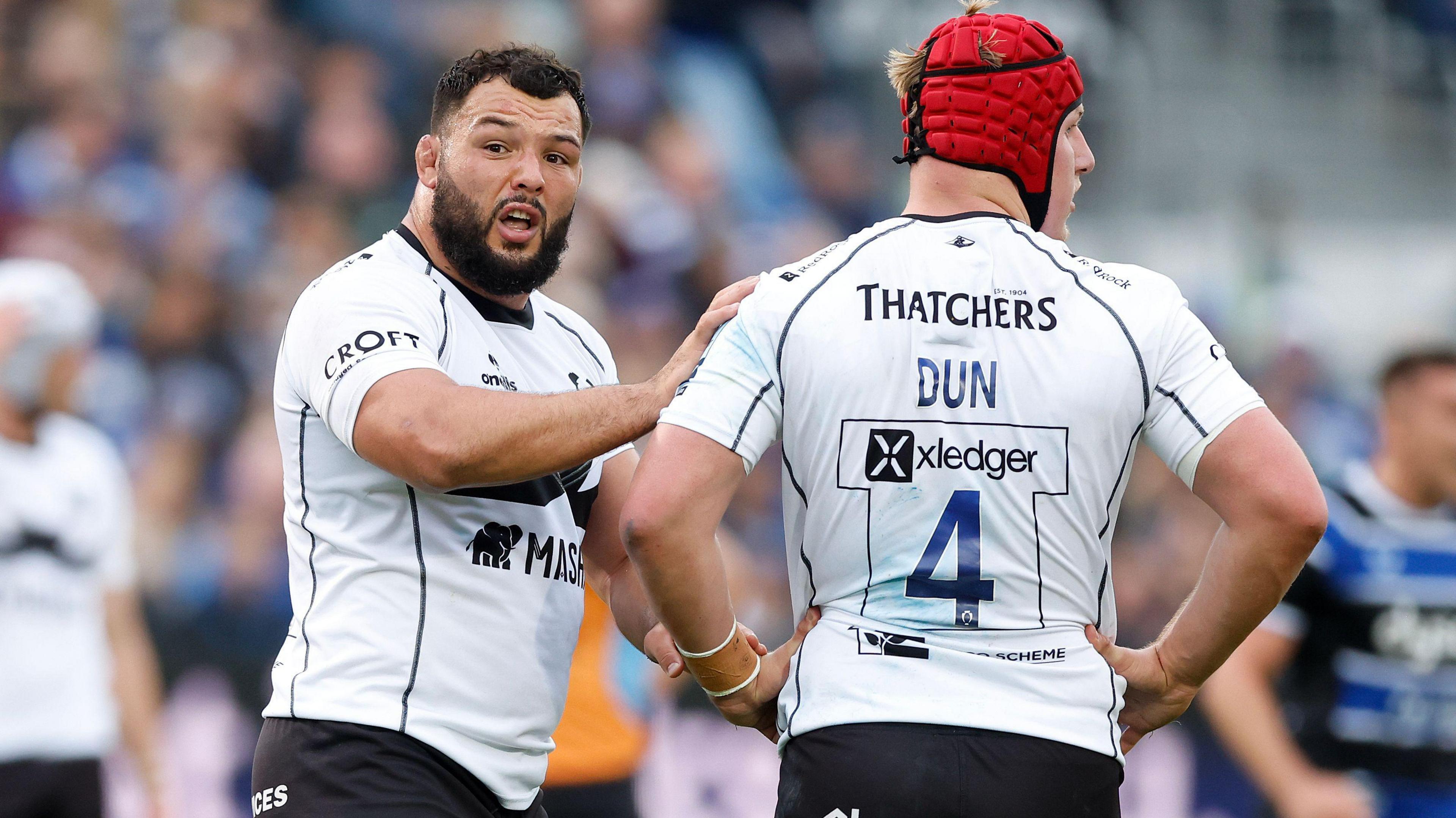 Ellis Genge (left) holds his right arm on the shoulder of his team-mate James Dun, who stands with his back to the camera 