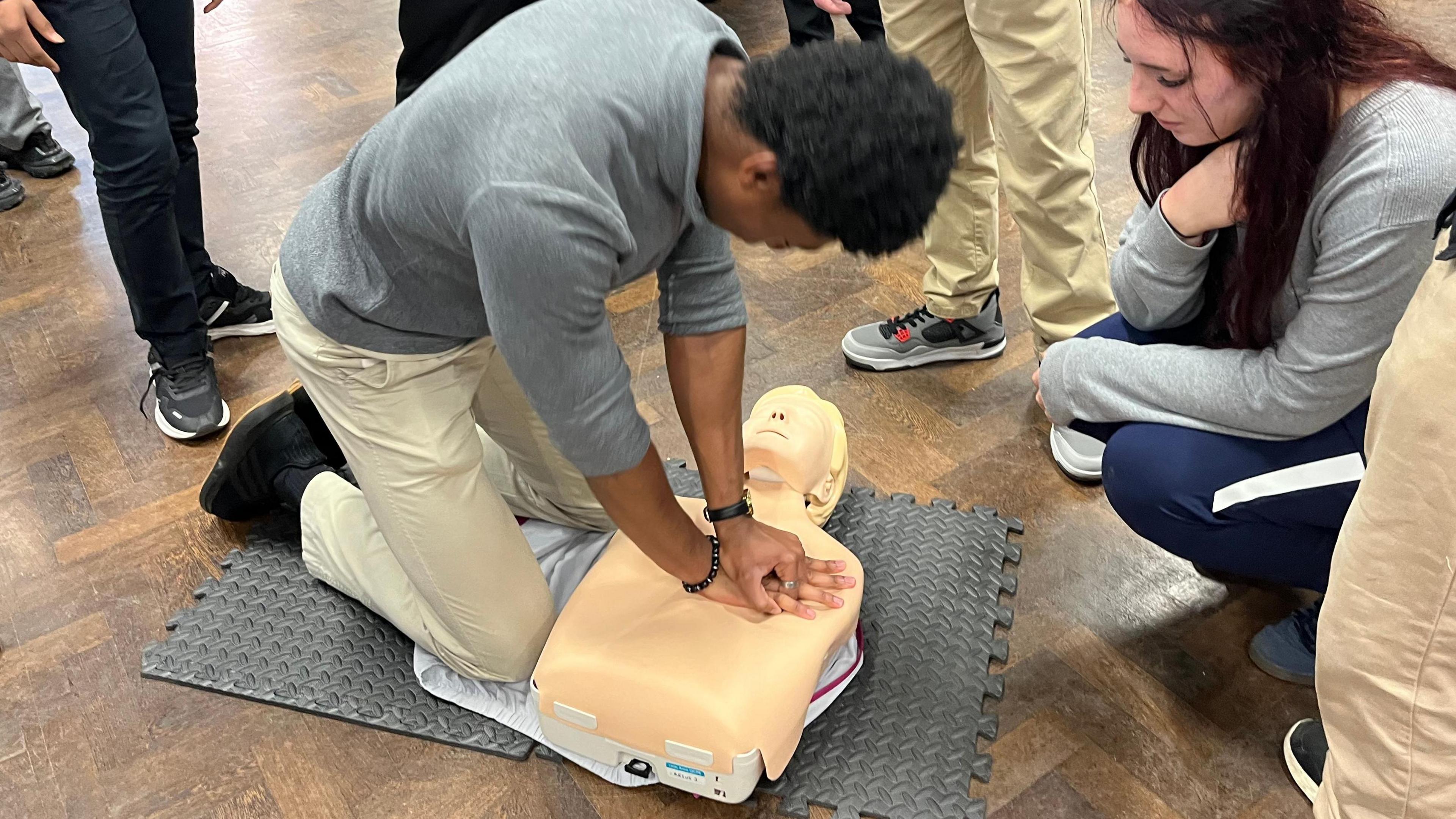 Resuscitation doll has CPR performed on it by student in school hall at Holcombe Grammar in Chatham