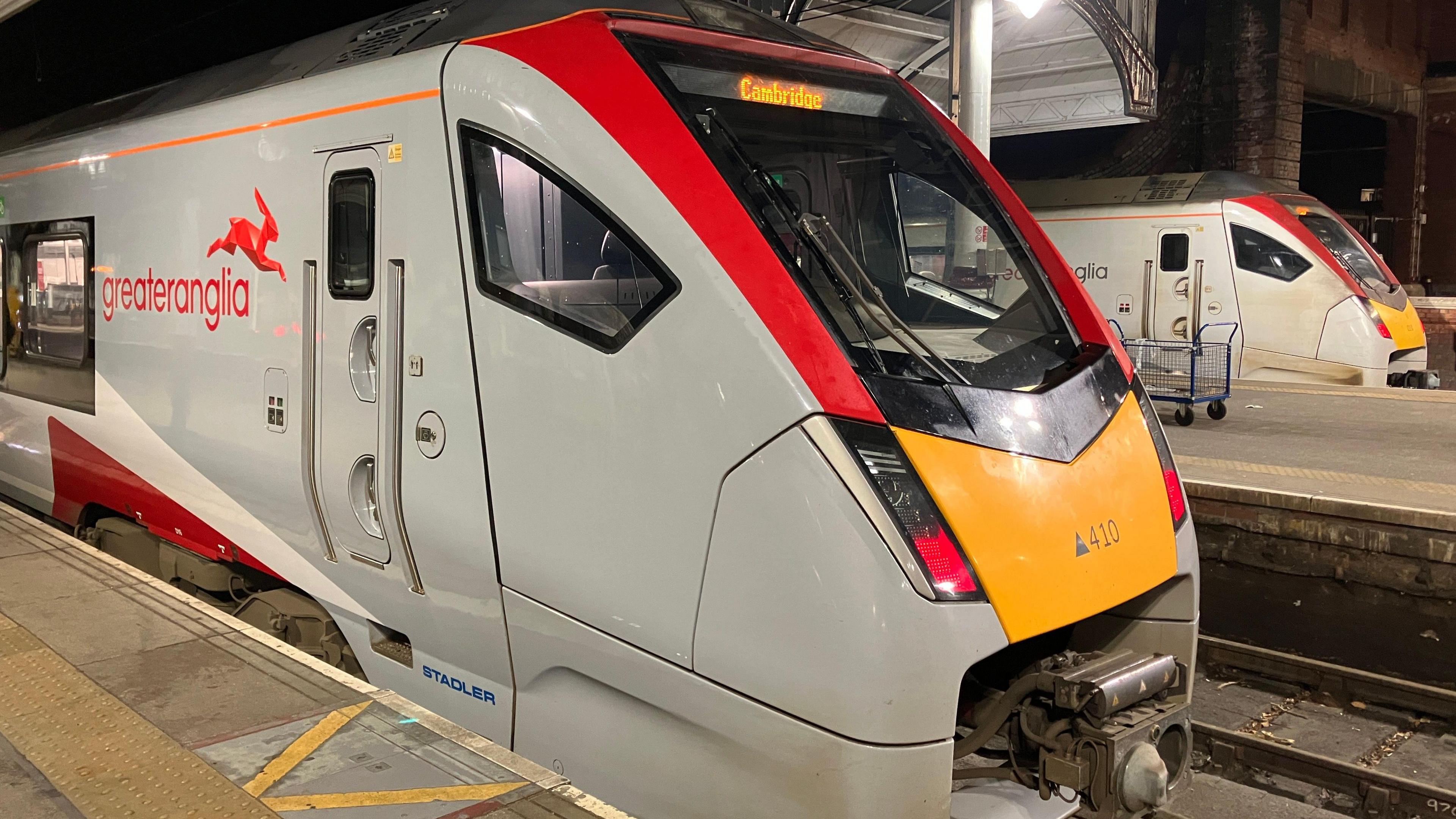 A grey, white and red Greater Anglia train sits at Norwich railway station.