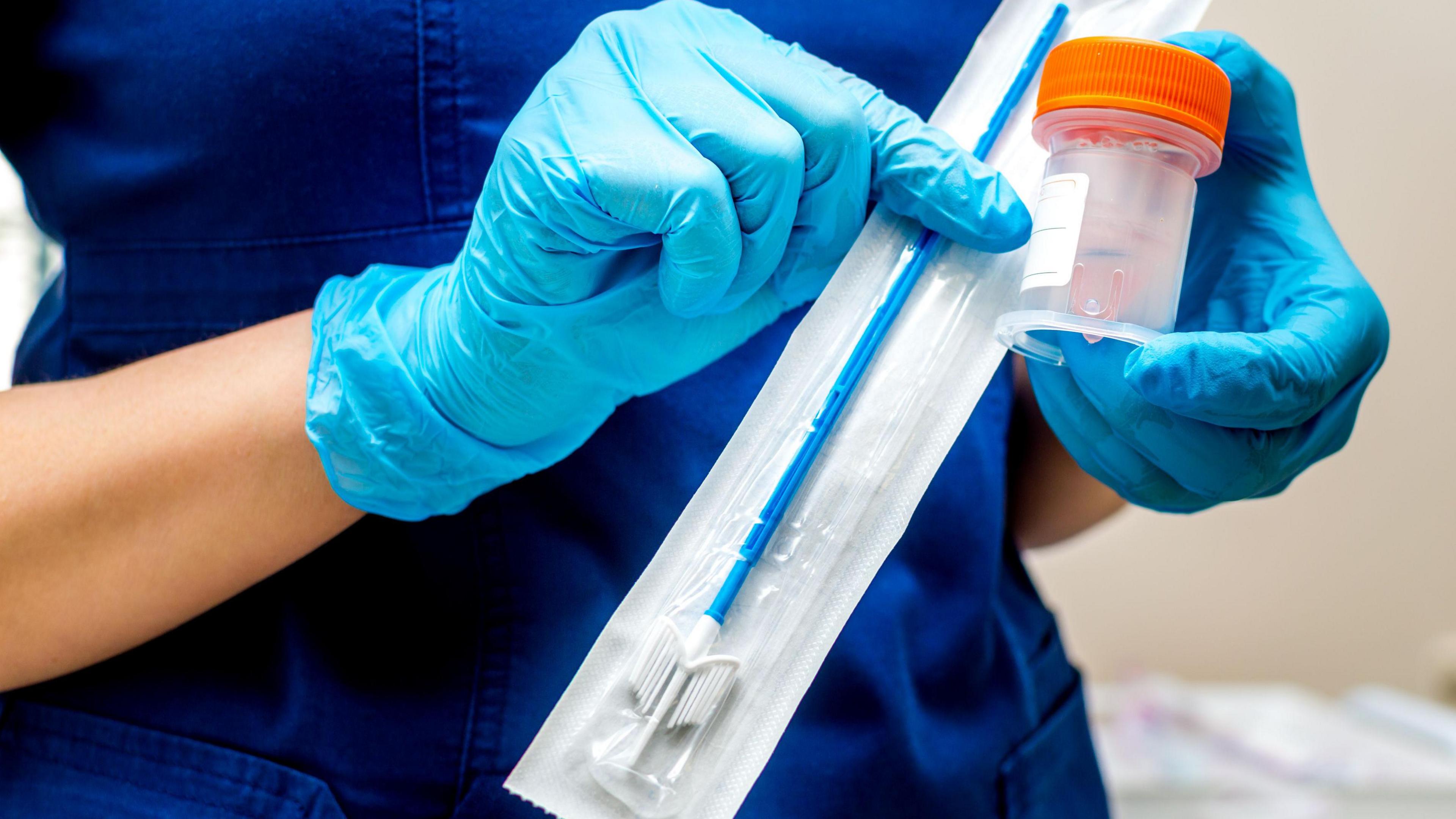 Blue gloved hands holding a brush for sampling liquid cytology