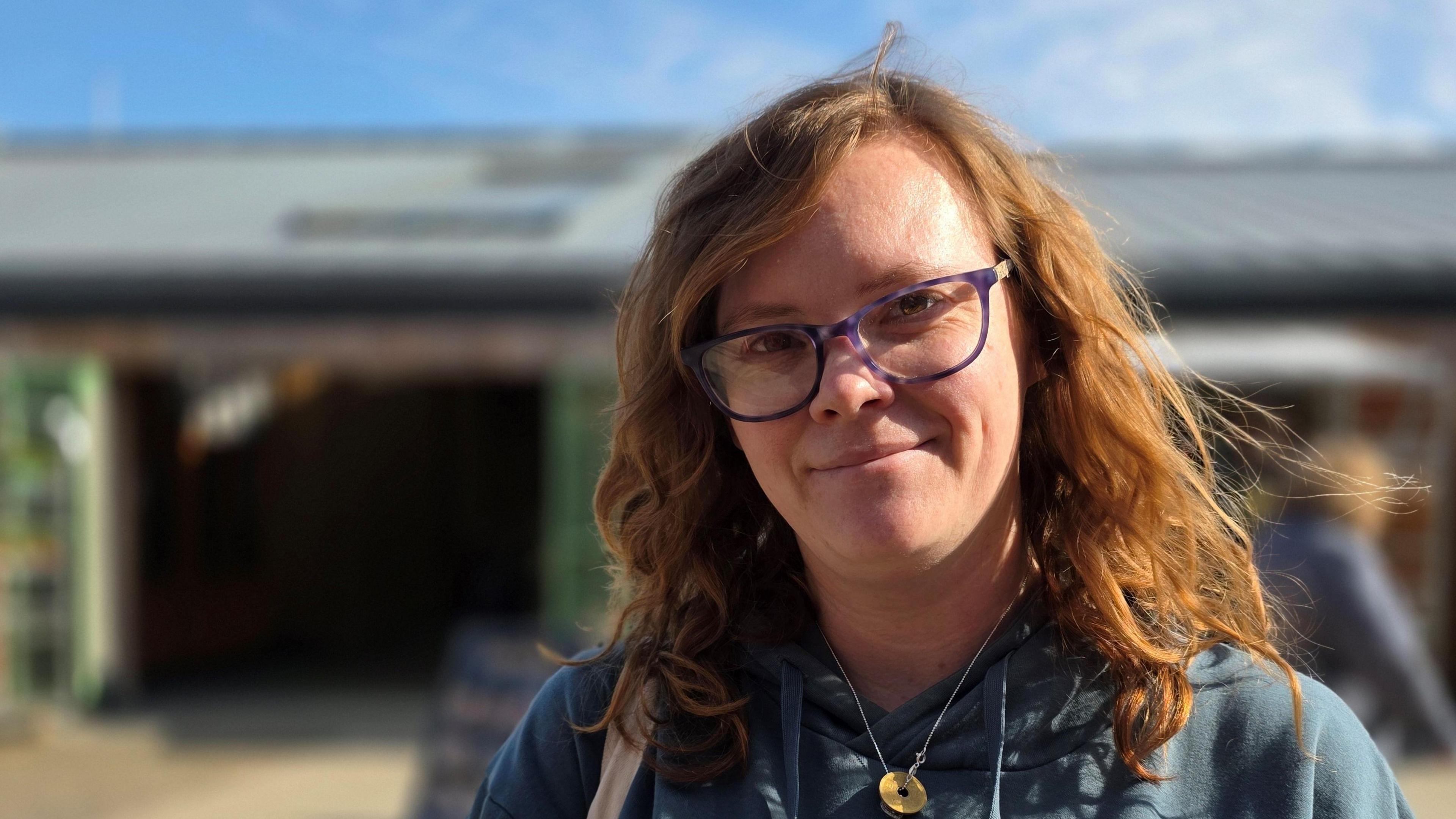 Cherrise Pollard is standing in front of market stalls in Great Yarmouth. She's wearing glasses and a blue top.