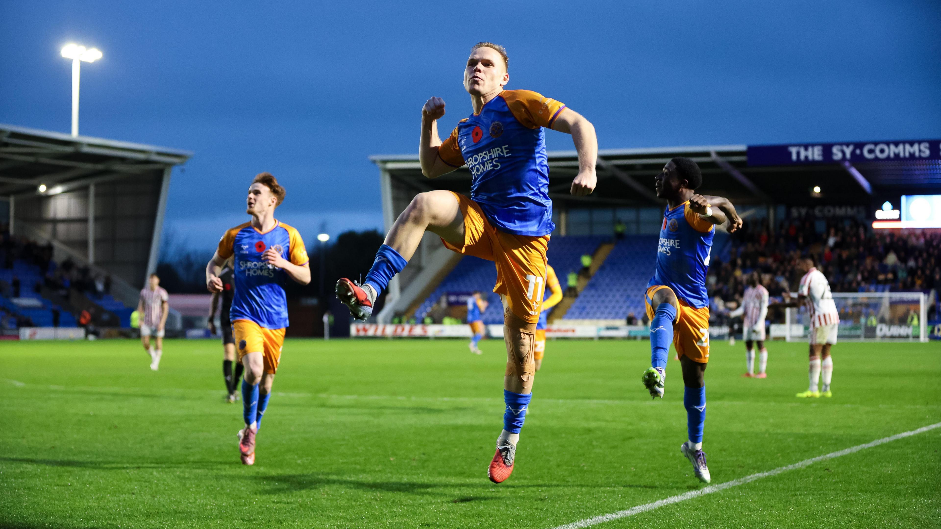 Anthony Scully leaps in air punching after scoring goal, flanked by two team mates