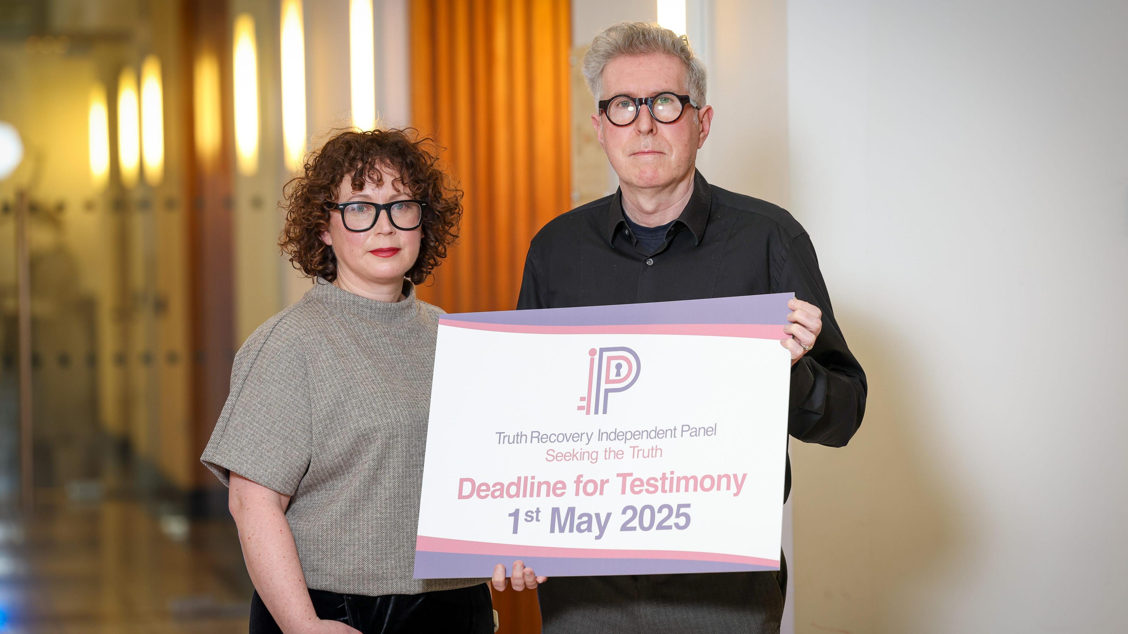  Prof Leanne McCormick and Prof Sean O'Connell hold a piece of card with the words dead for testimony 1 May 2025 