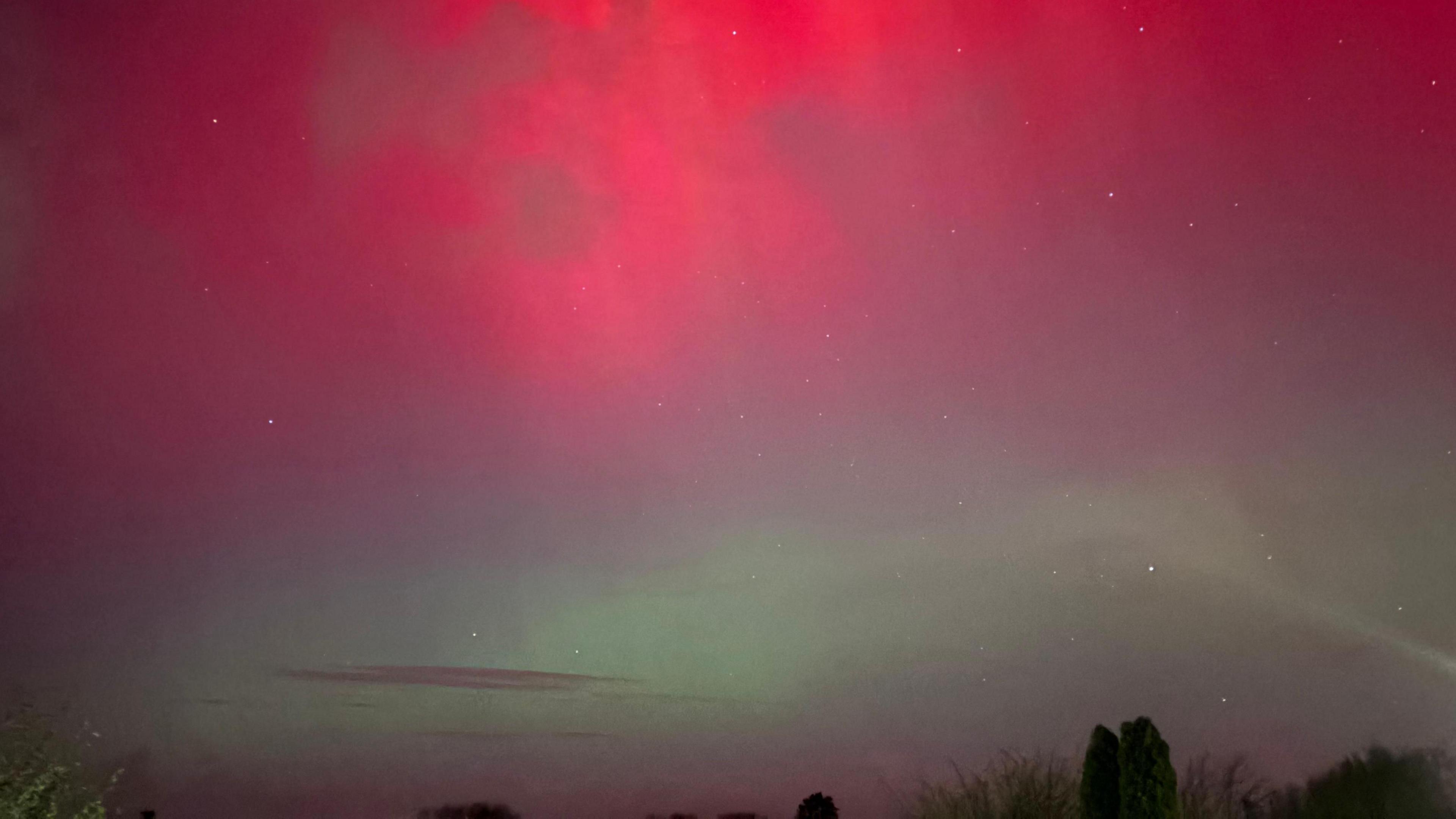 The sky over Lancaster is split by the lights, the top half glows red the bottom half is a faint green
