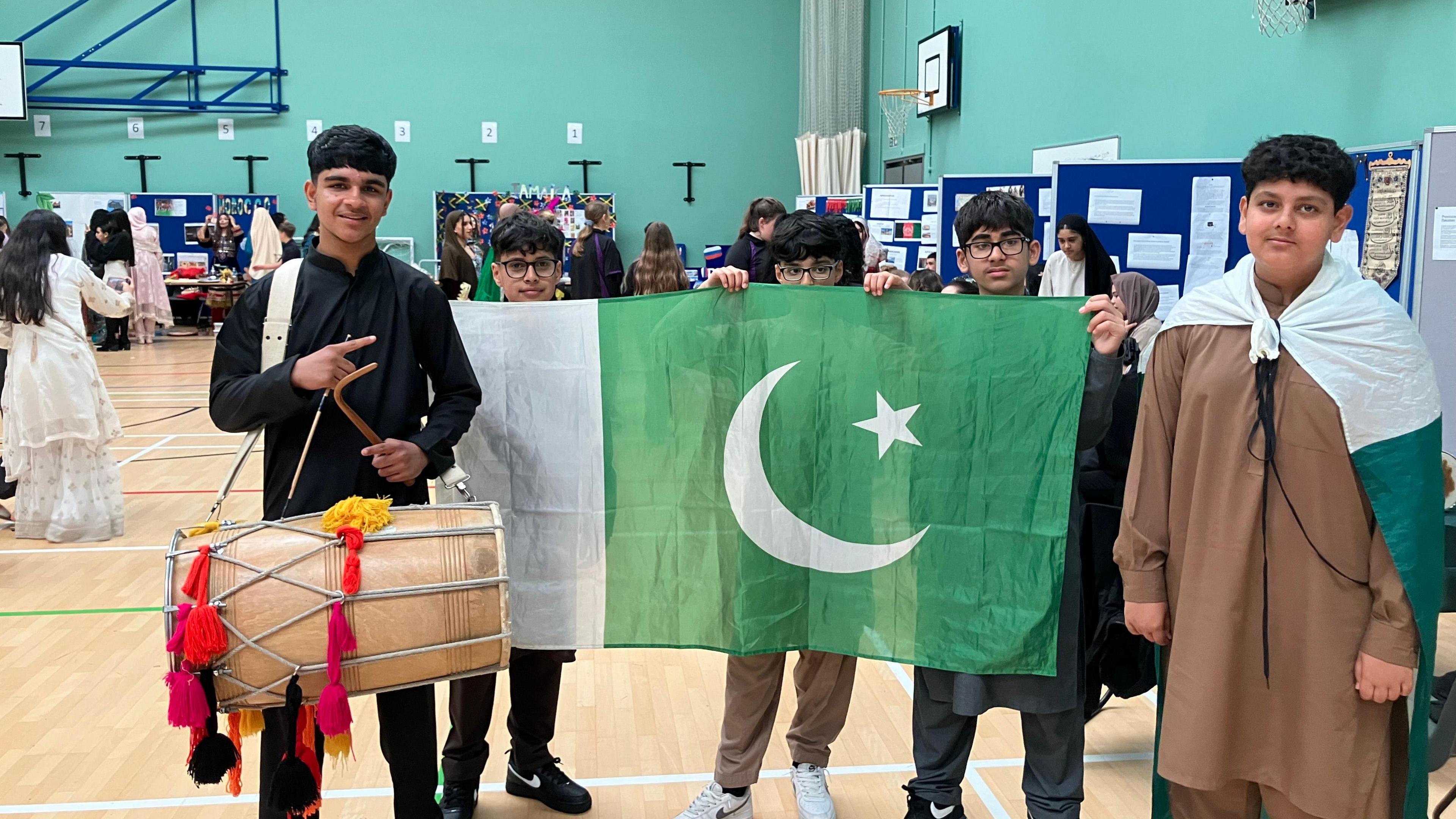 Four boys posing with the Pakistan flag smiling at the camera