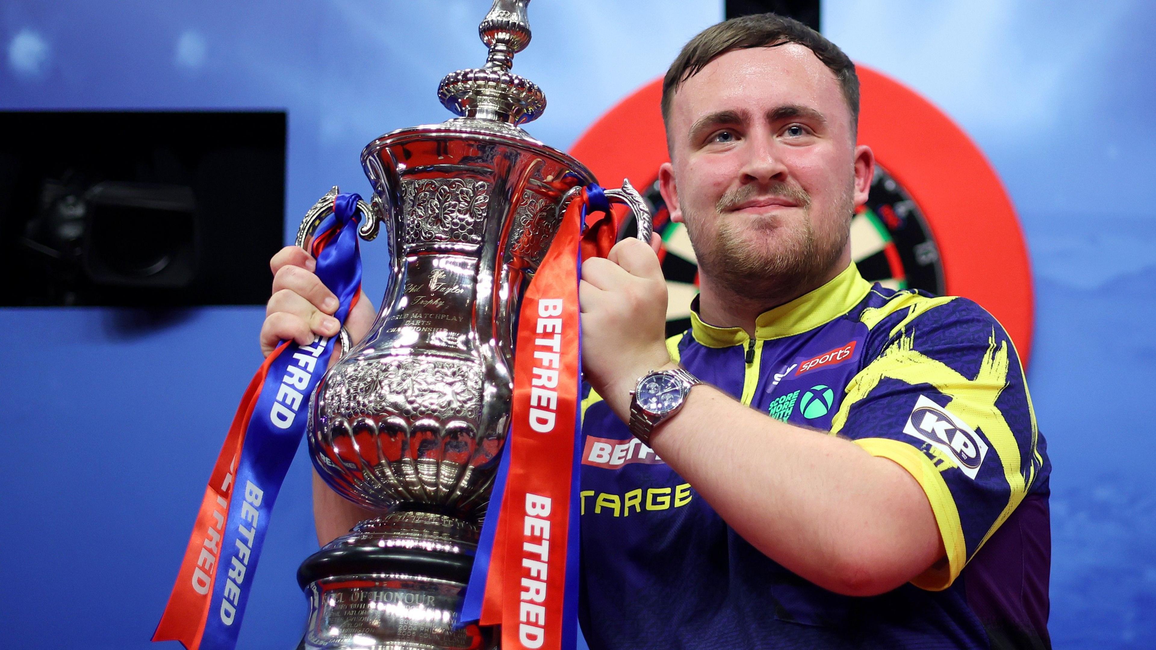 Luke Littler holds the Phil Taylor Trophy