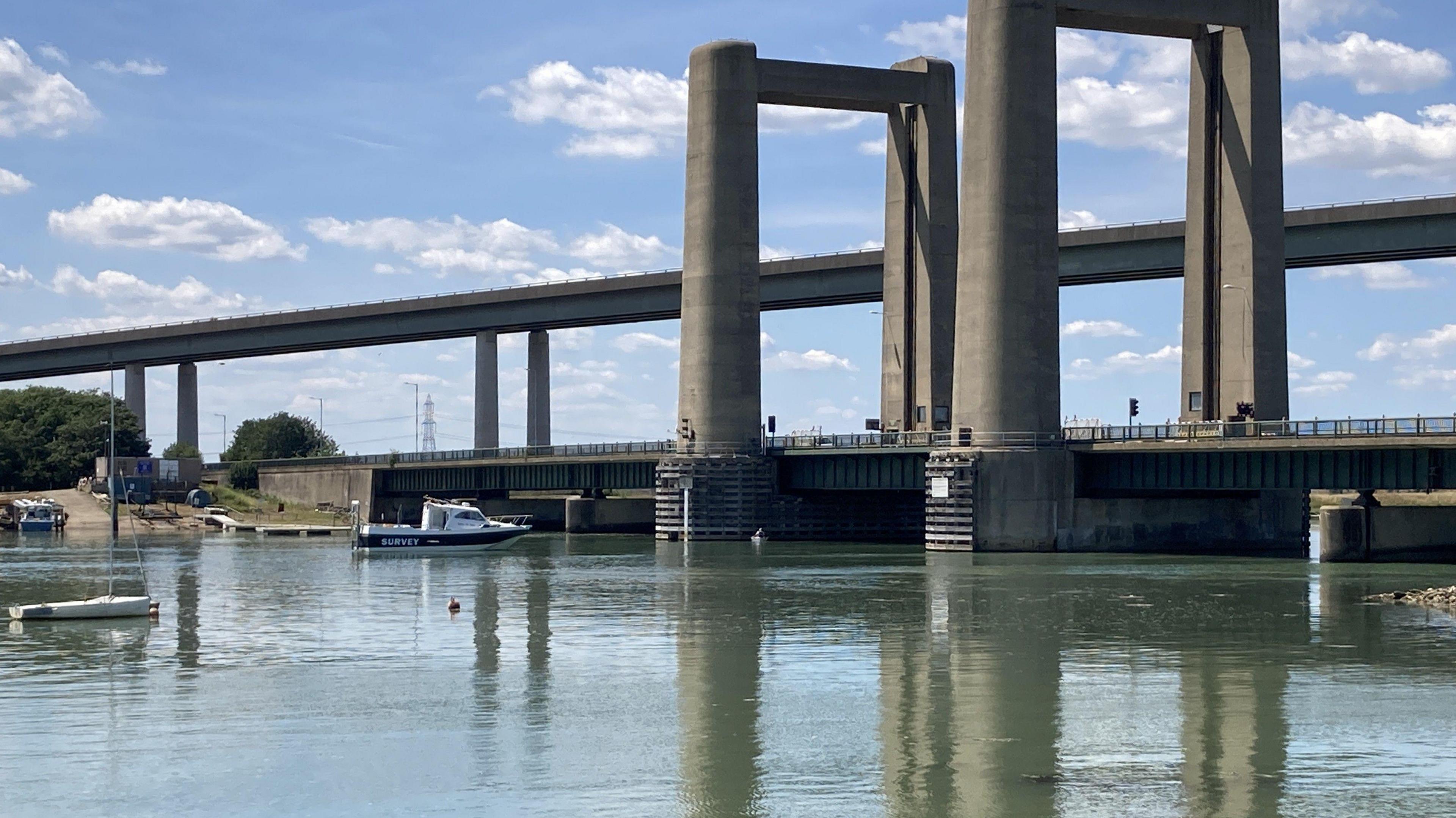 The Kingsferry Bridge, a concrete structure dating from 1960, with a small survey vessel in the foreground.