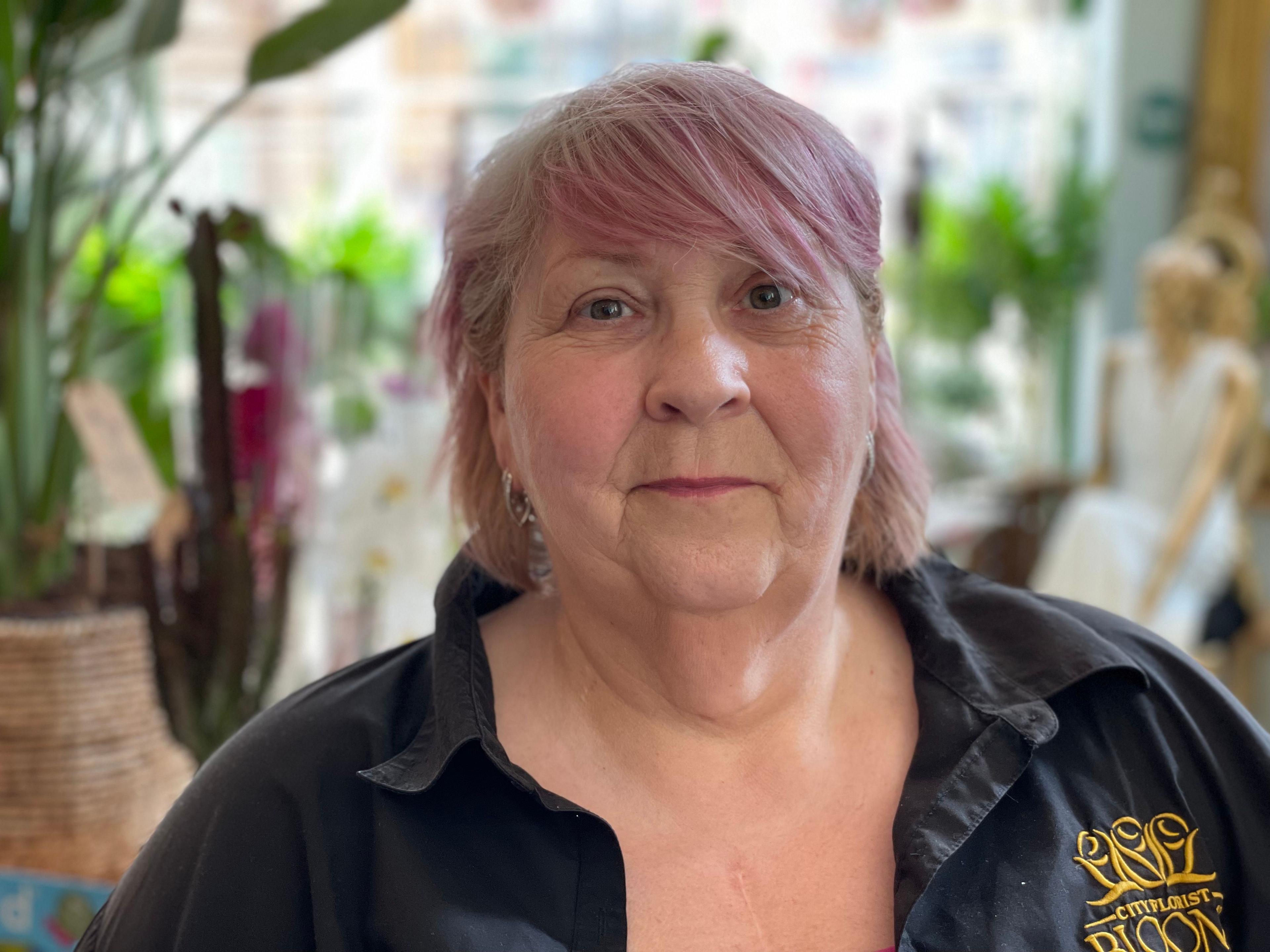 Florist Ann Fawcett wearing a black shirt with the name of her business embroidered on it