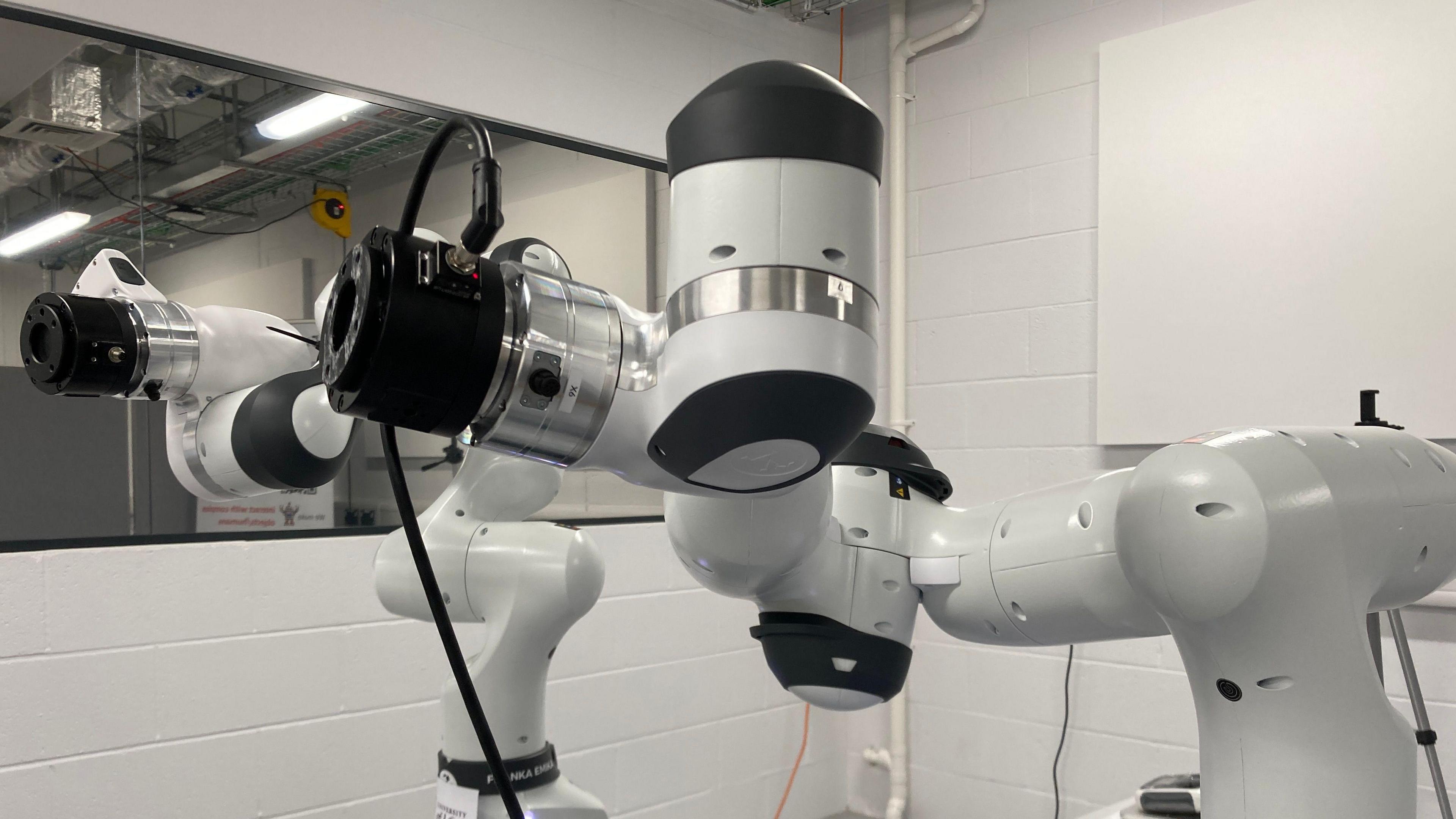 Two white and black robotic arms in a laboratory setting