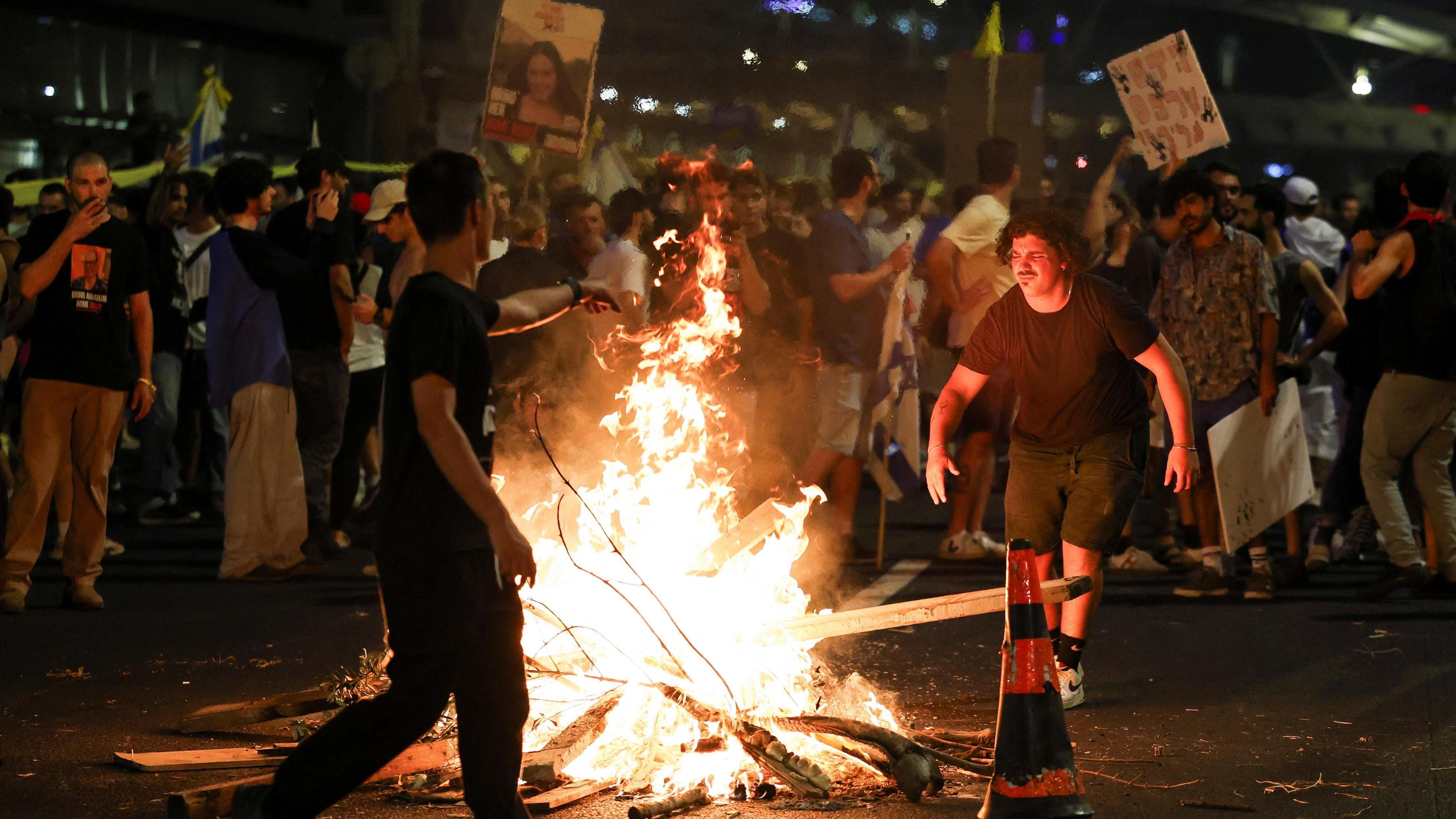 Protesters rally against the government around a fire and holding placards, to show support for the hostages who were kidnapped during the deadly October 7 attack.