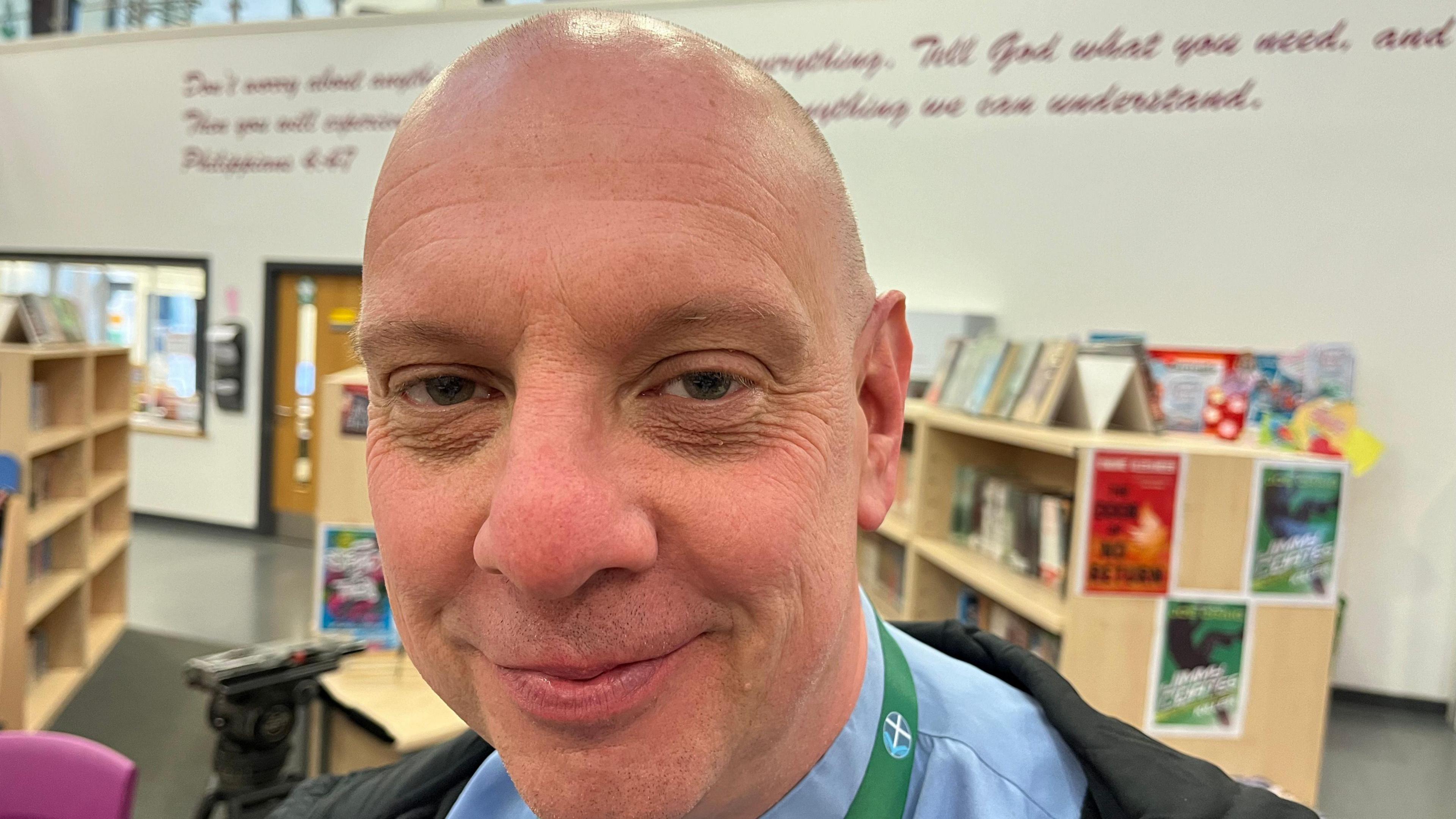 Deacon Seamus O'Looskan, Chaplain at St Paul's Catholic School stands in the school library.  
