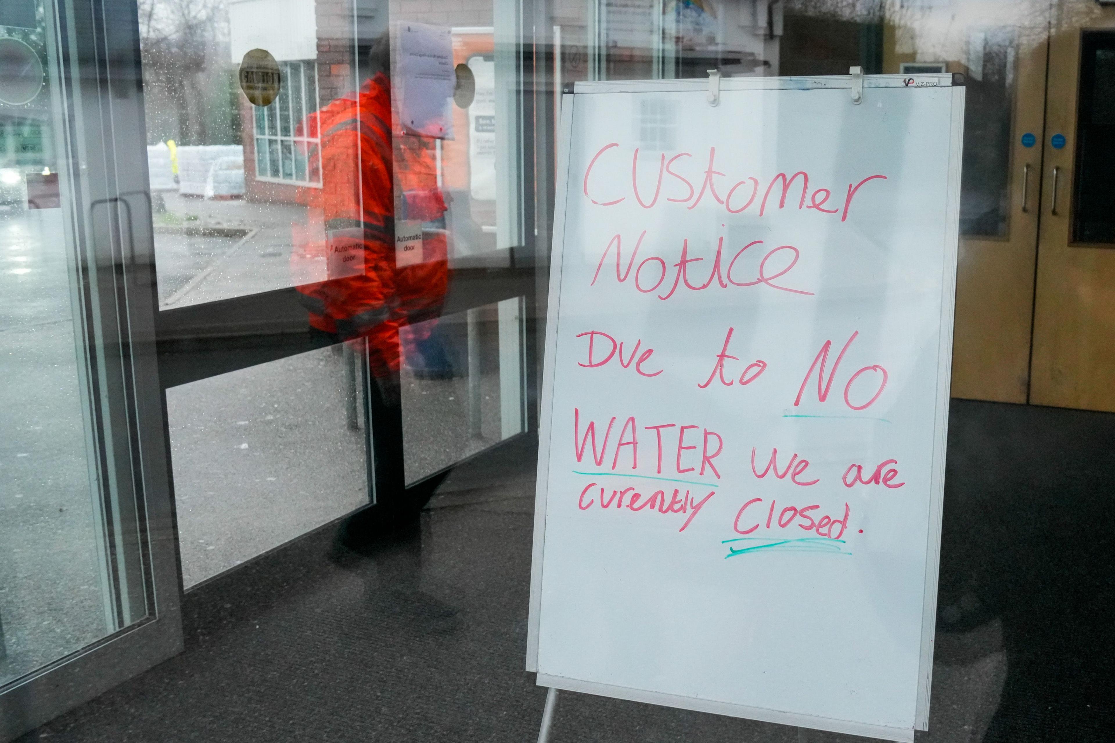 A whiteboard sits on the other side of a window. It says: "Customer notice. Due to NO WATER, we are currently closed. 