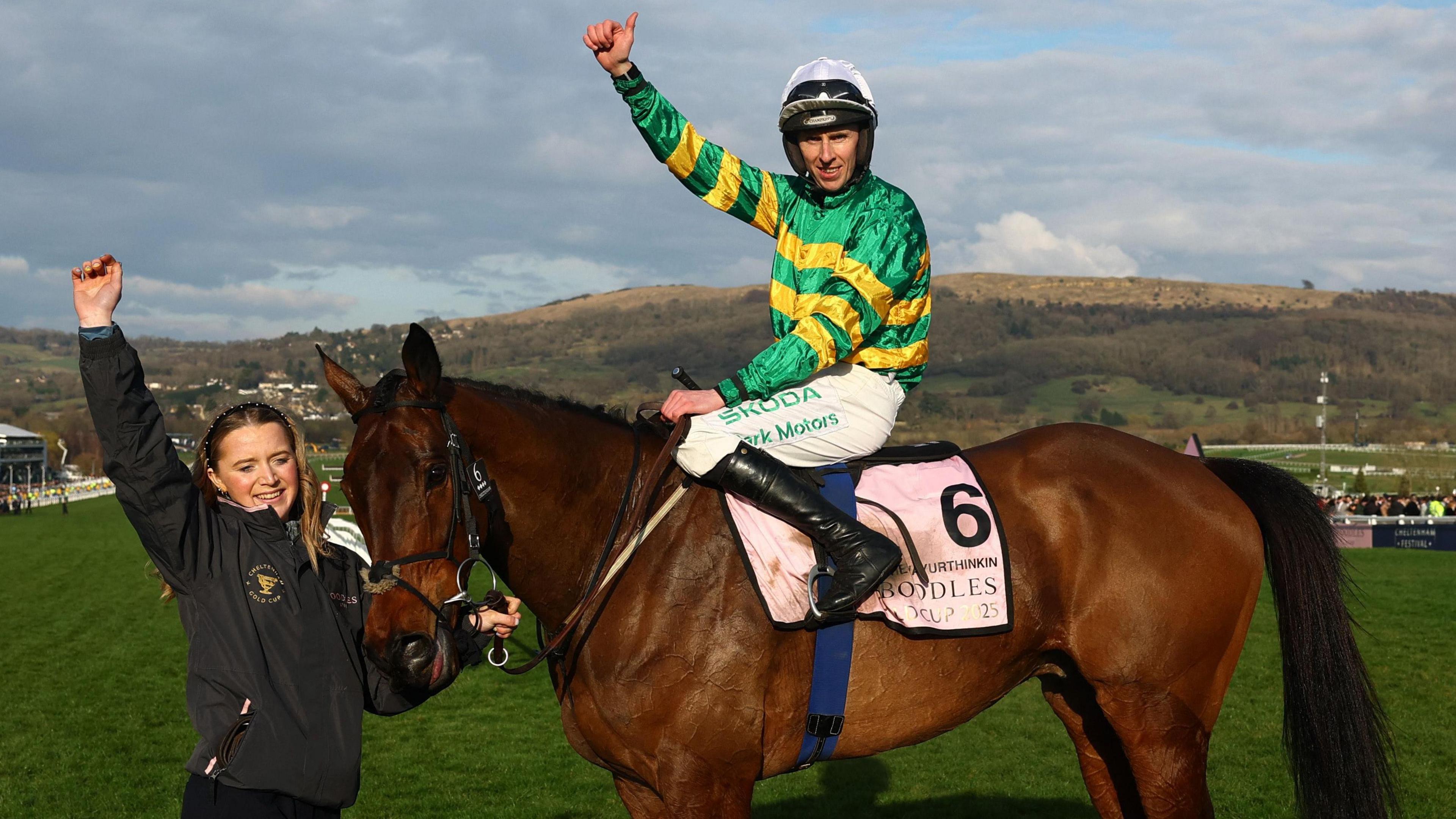 Mark Walsh riding a brown horse named Inothewayurthinkin. Mark is wearing a green and yellow striped top and looks at the camera with one hand raised in the air with his thumb up. A woman can be seen in the picture near the horse's head with her hand raised.