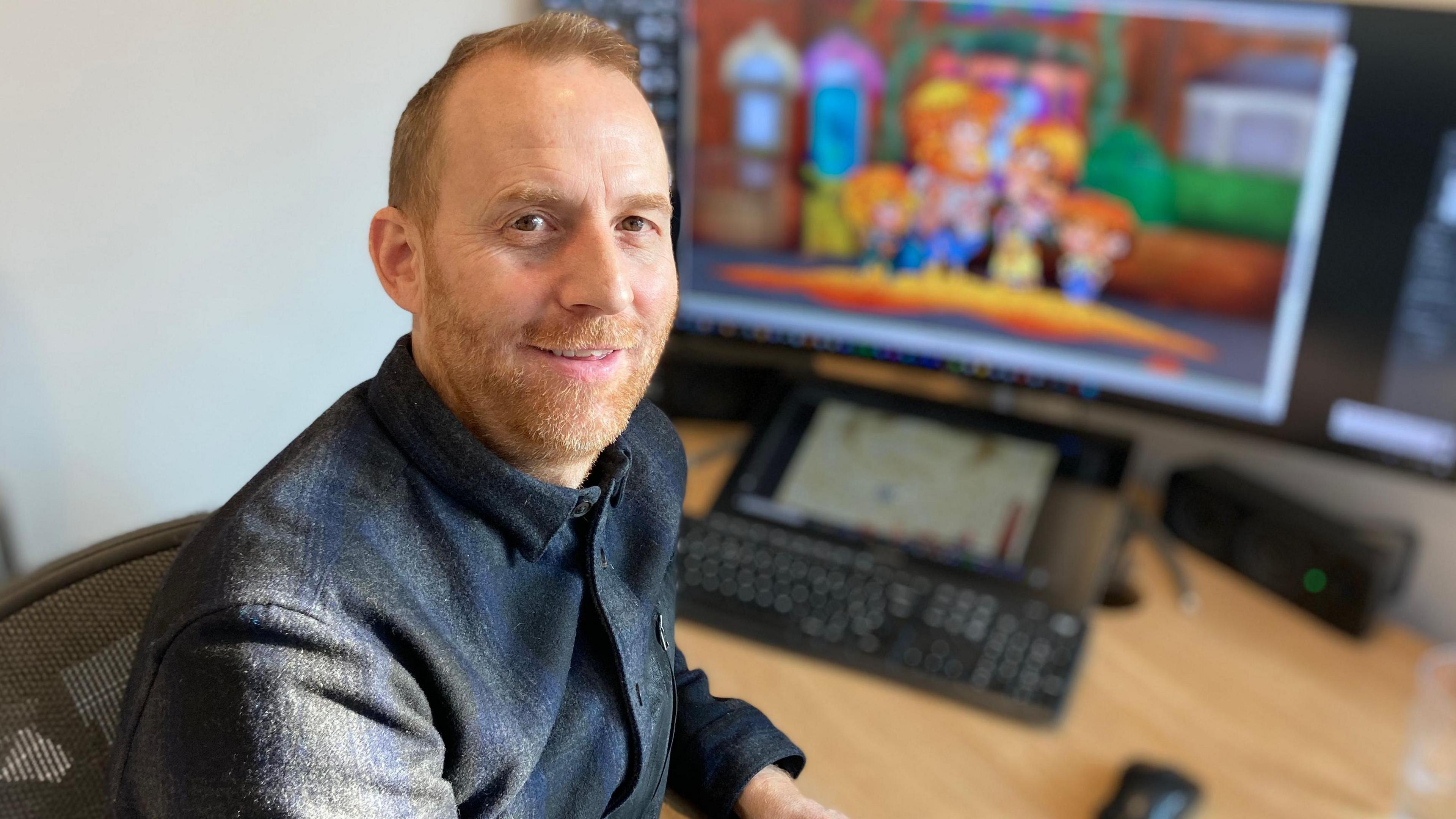 Eliot Wykes sitting in front of his computer screen while looking straight into the camera