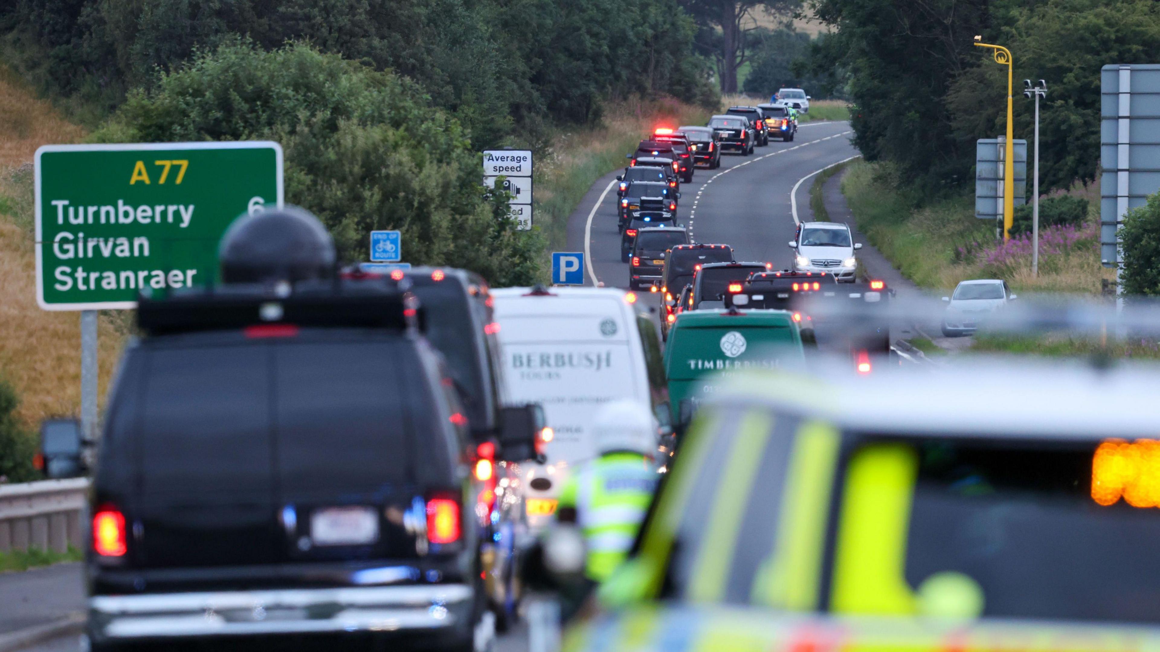Trump's motorcade on the A77 in Maybole, South Ayrshire, with other vehicles following behind.