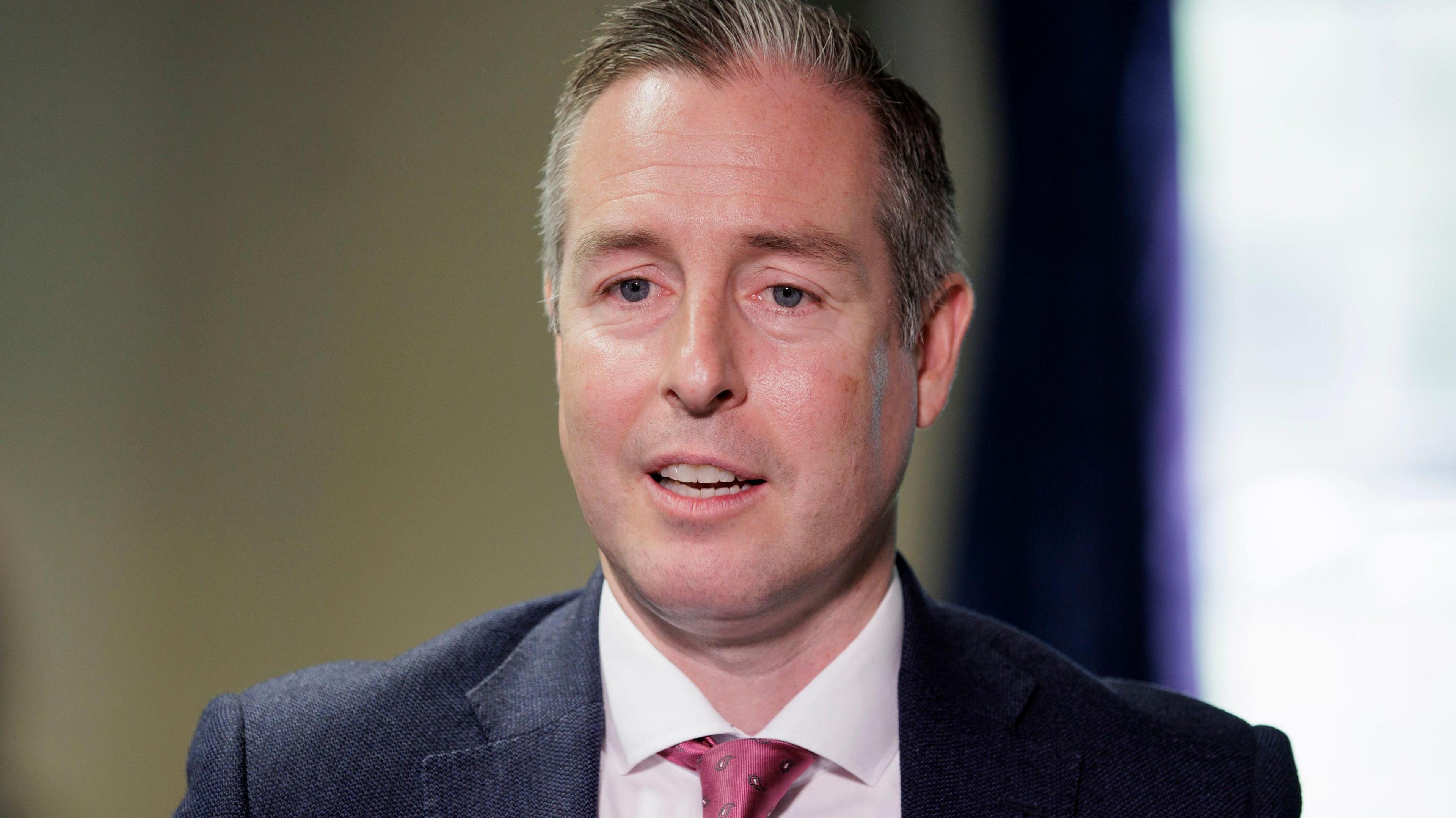 Image shows head and shoulders photo of Paul Givan as he is speaking. He is wearing a suit and tie