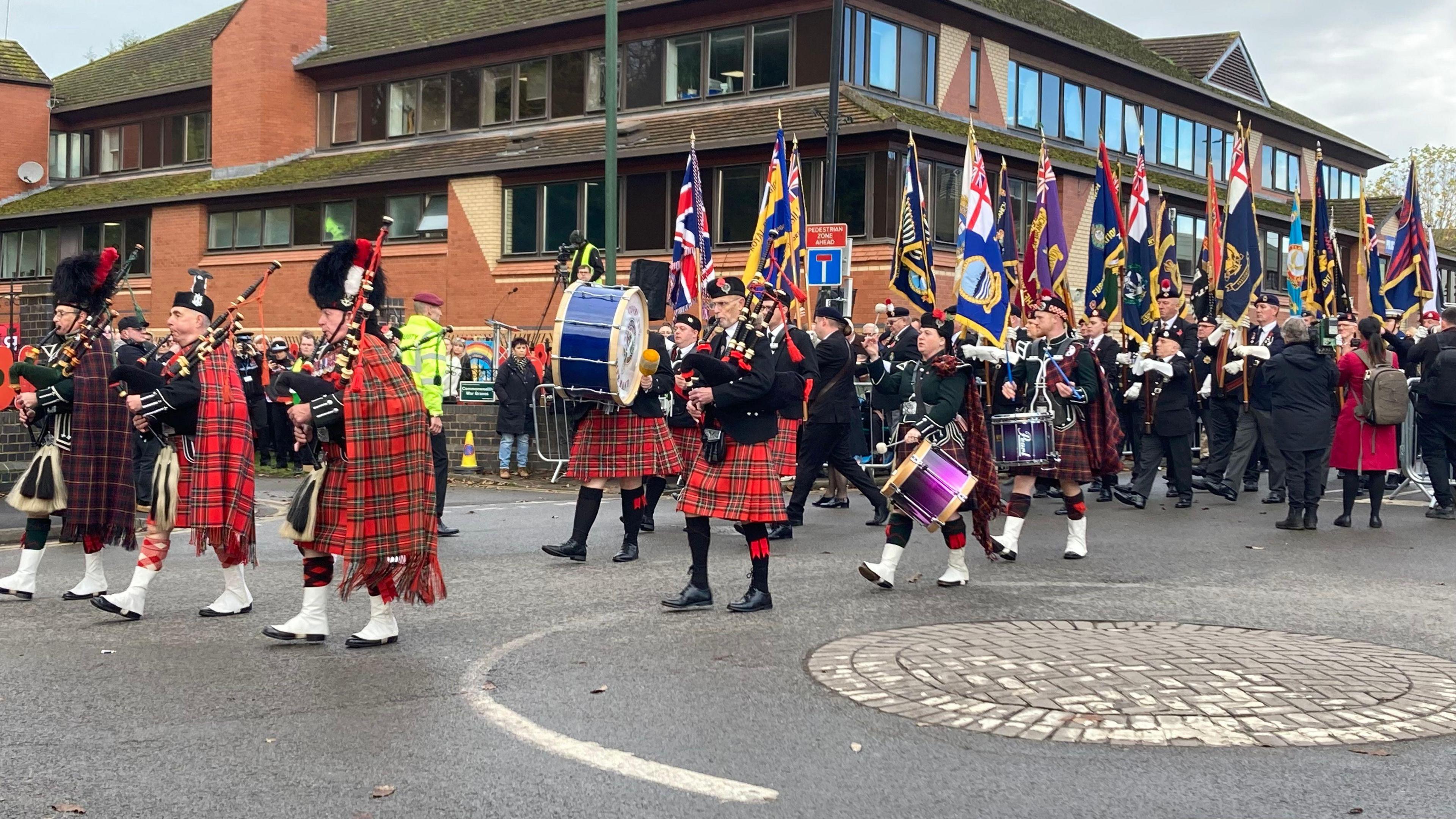 A parade marches through a town centre as part of Armistice Day celebrations.