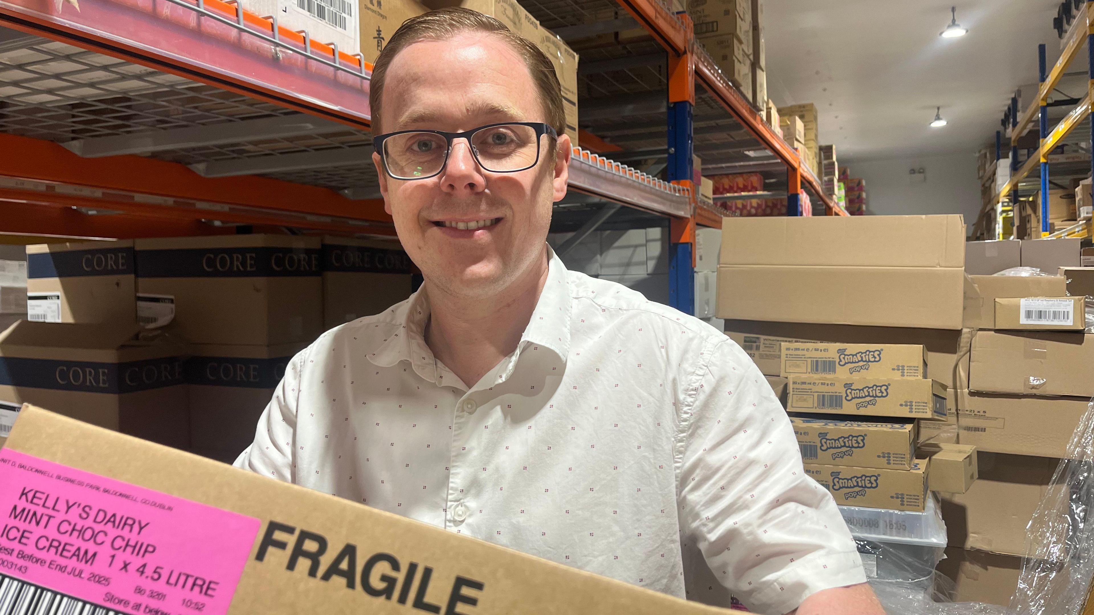 Ryan Thompson holding cardboard box with words 'fragile' and 'Kelly's Dairy mint choc chip ice cream' written on side