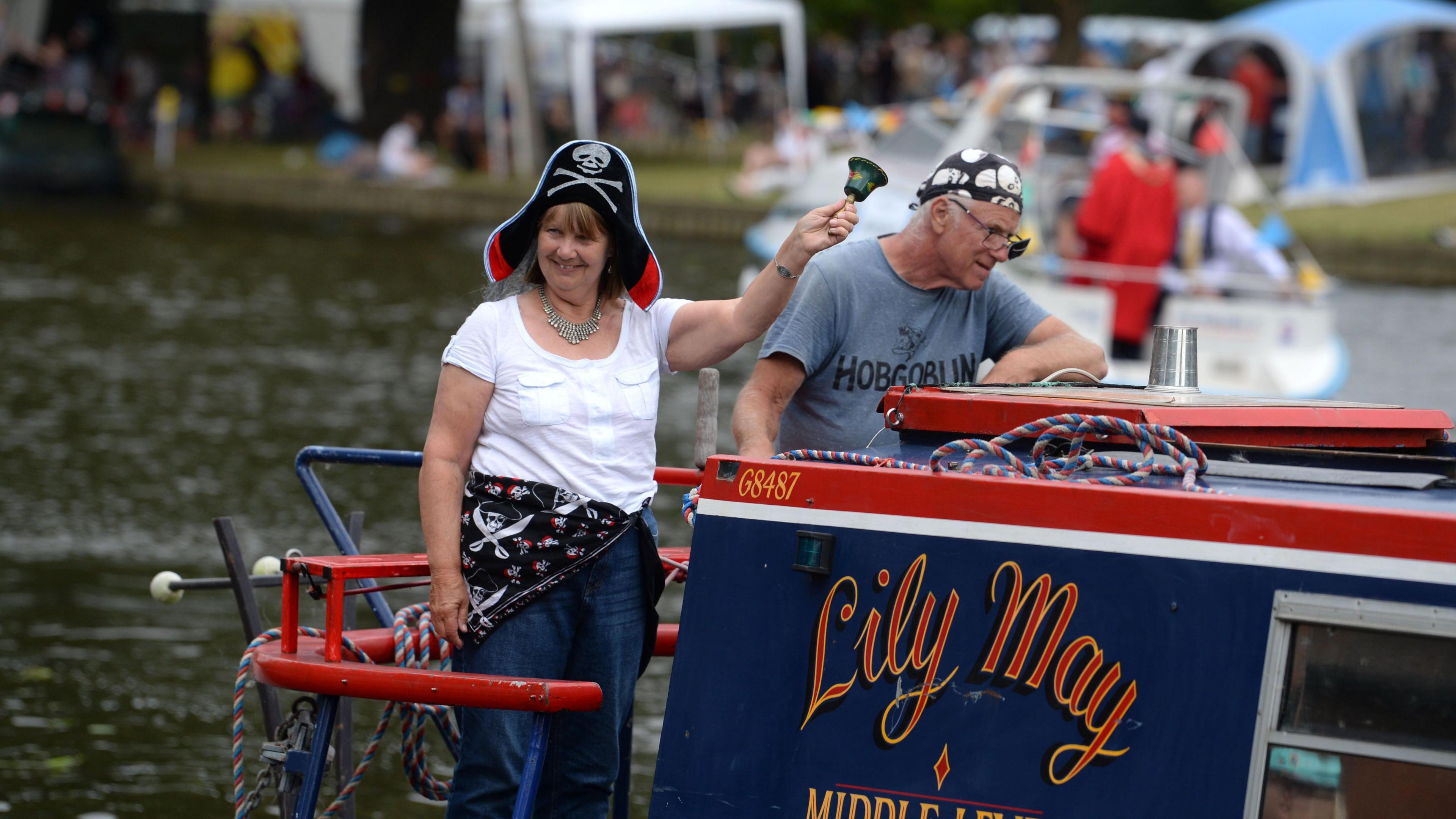 Two people with pirate hats on standing on a barge, on the River Great Ouse, in Bedford