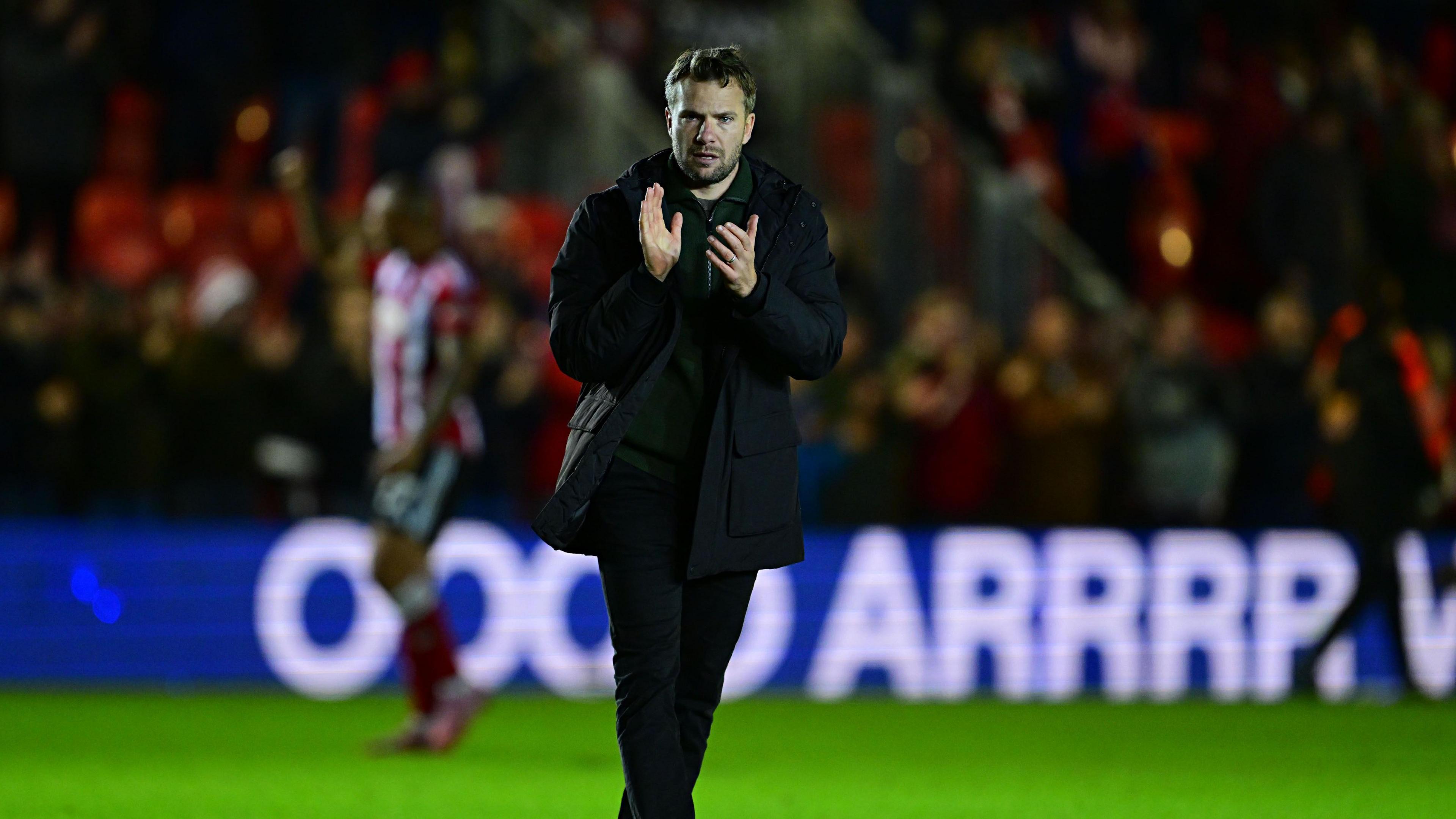 Plymouth Argyle head coach Tom Cleverley claps the fans as he walks across the pitch after defeat.