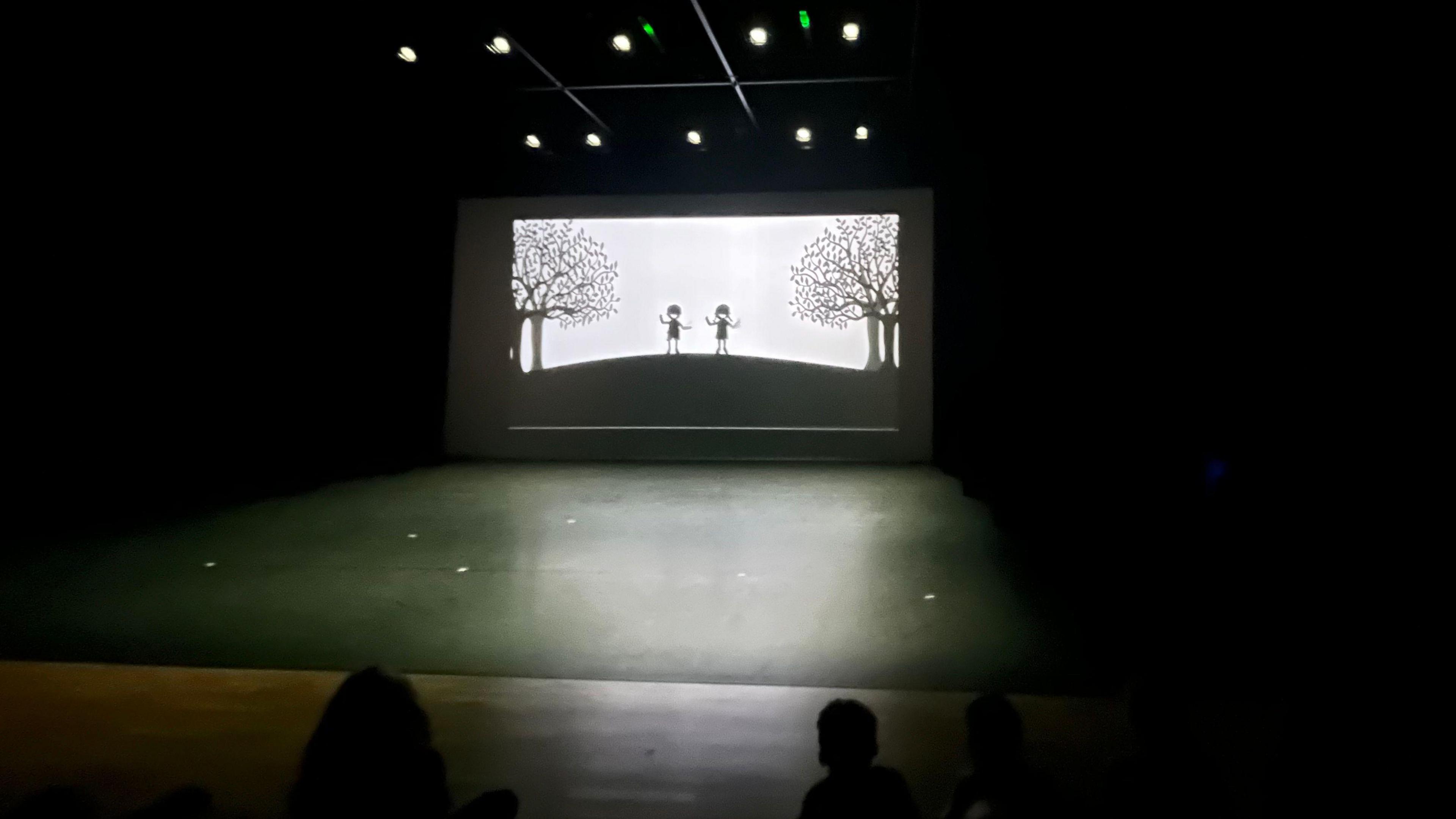 Picture showing stage with the silhouette of two children on a big screen