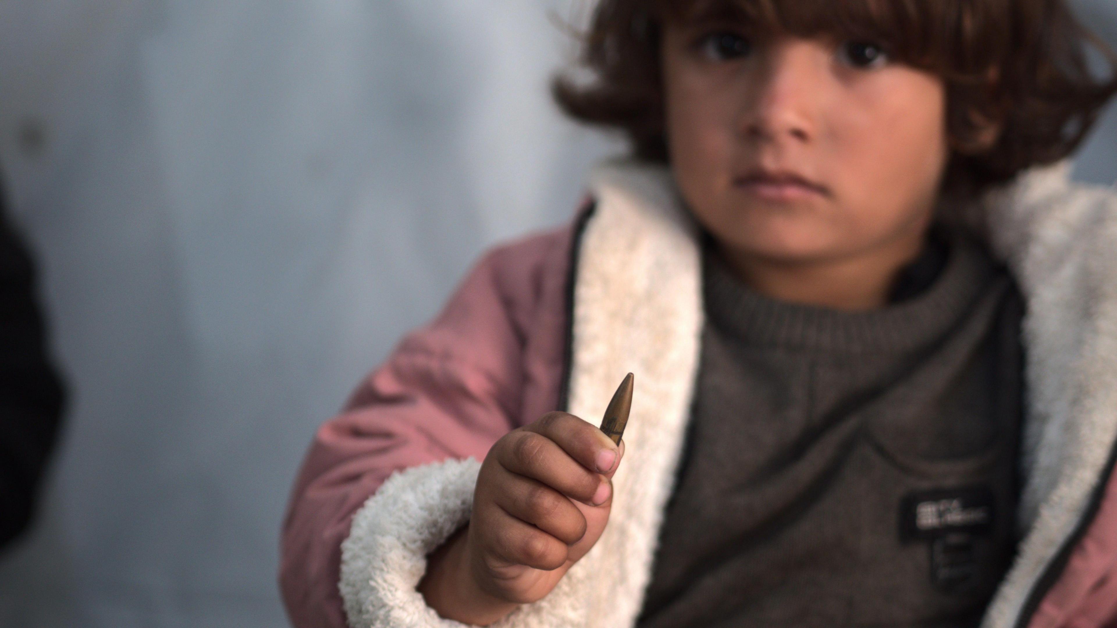 Three-year-old Palestinian girl Razan holds the bullet up to the camera which was safely removed from her neck