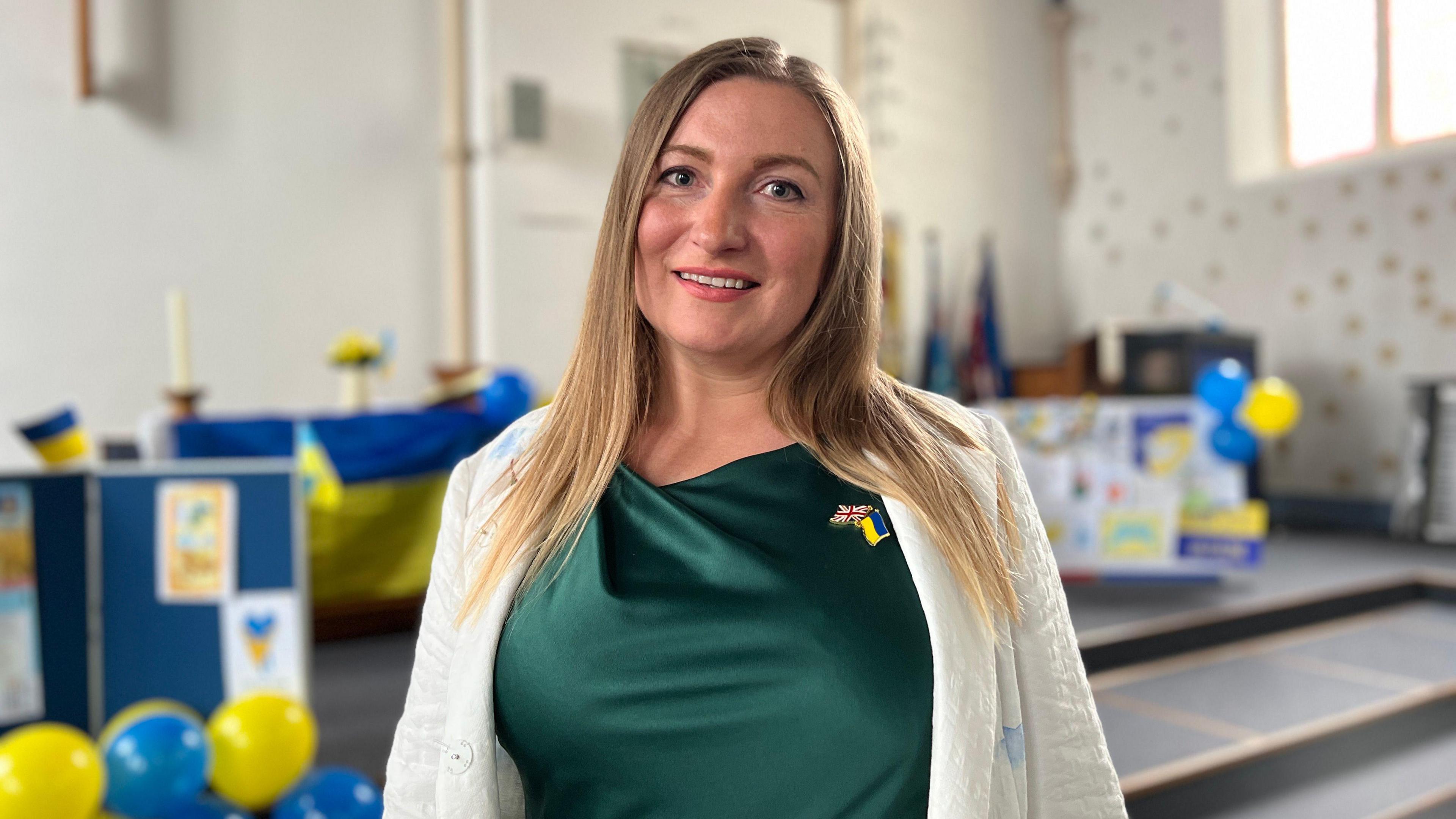 Antonina Grebeniuk looks at the camera wearing a green top with yellow and blue balloons behind her