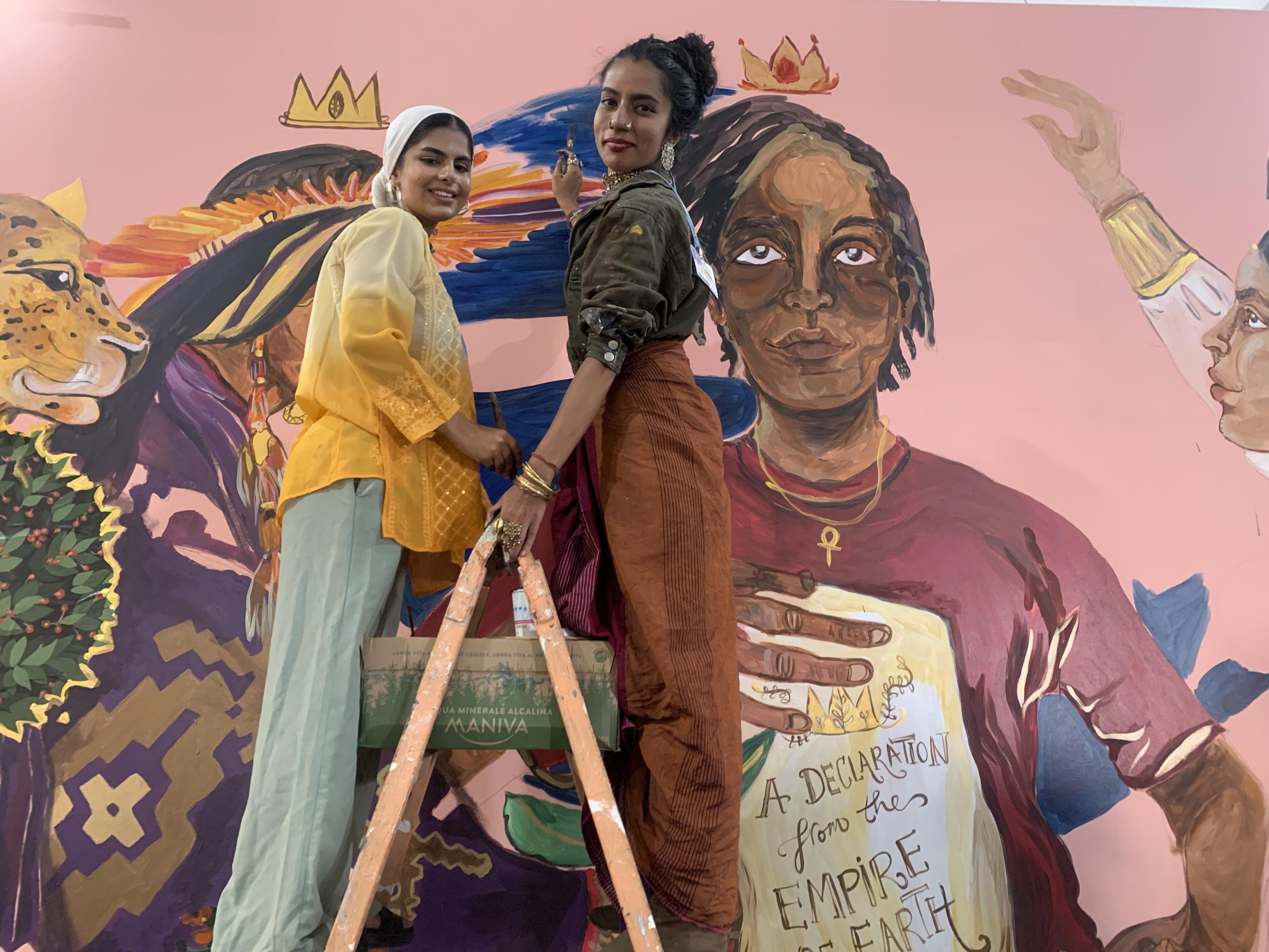 Ayisha Siddiqi(left) paints a mural at the first Youth Pavilion at a COP summit