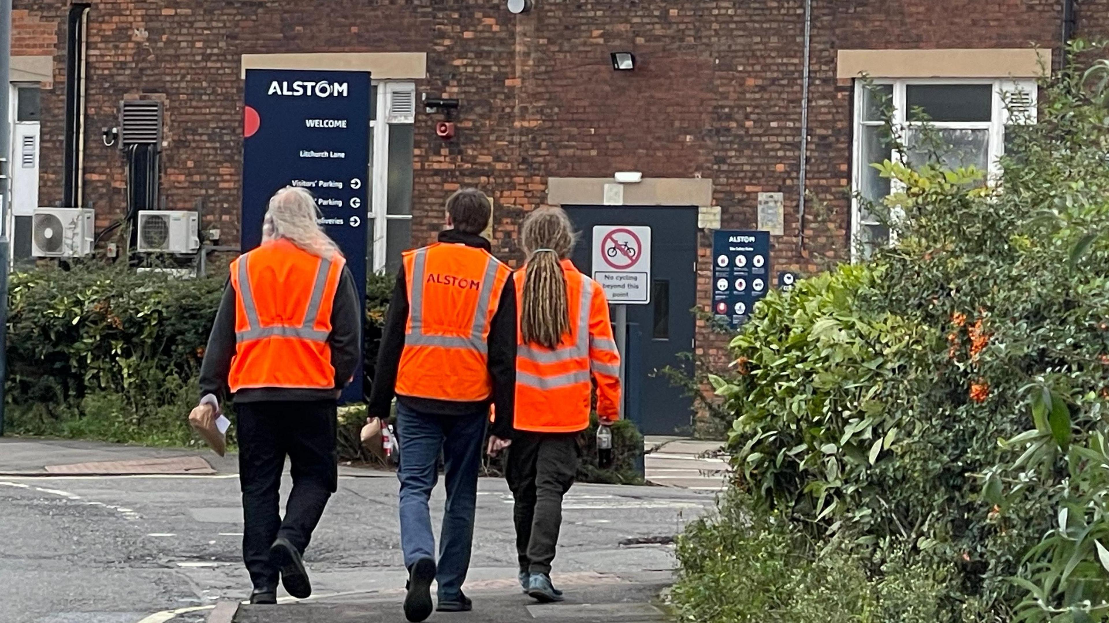 Three people in high-vis vests