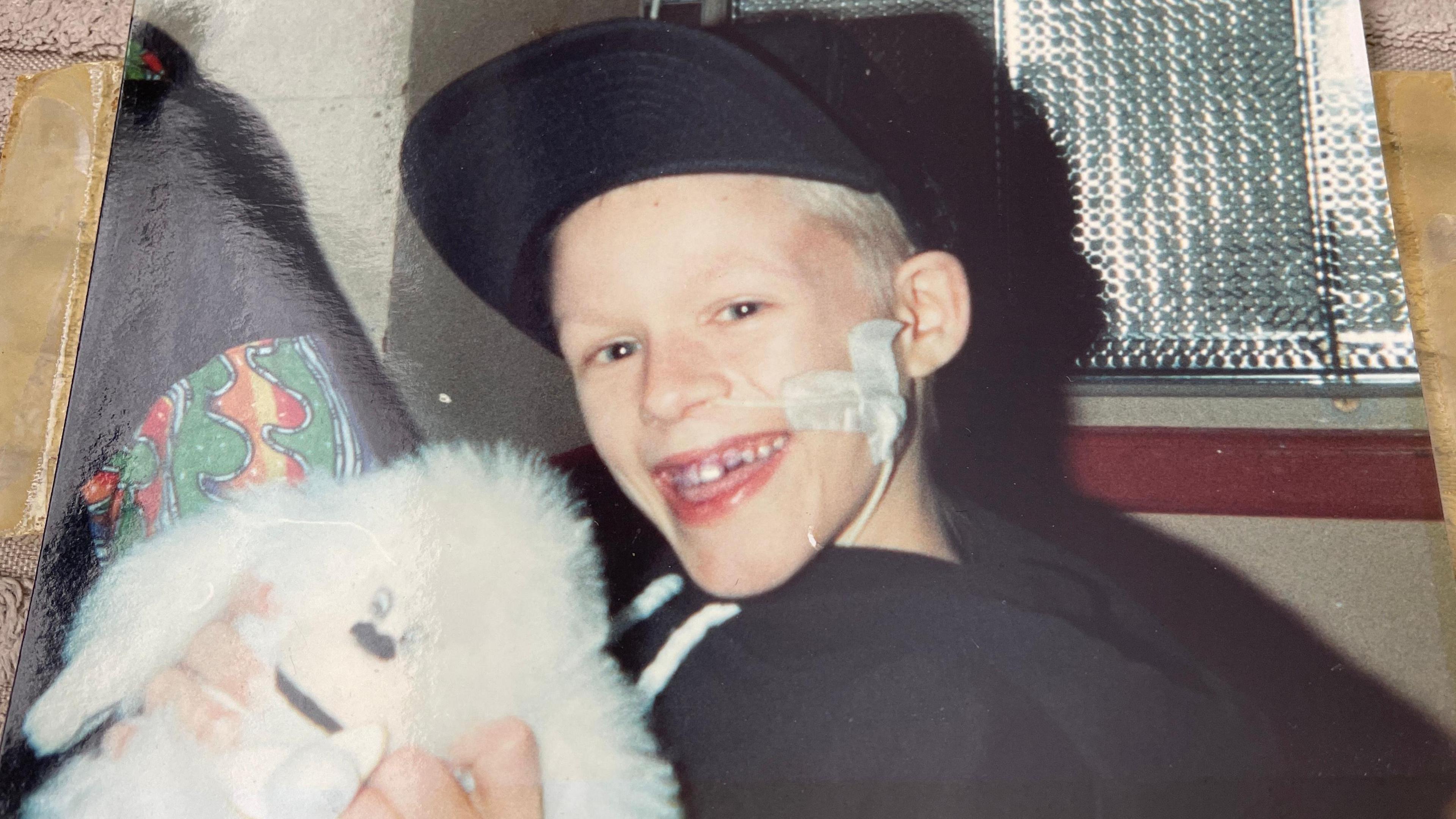 Image of Lee Turton smiling at the camera while holding a white, fluffy toy